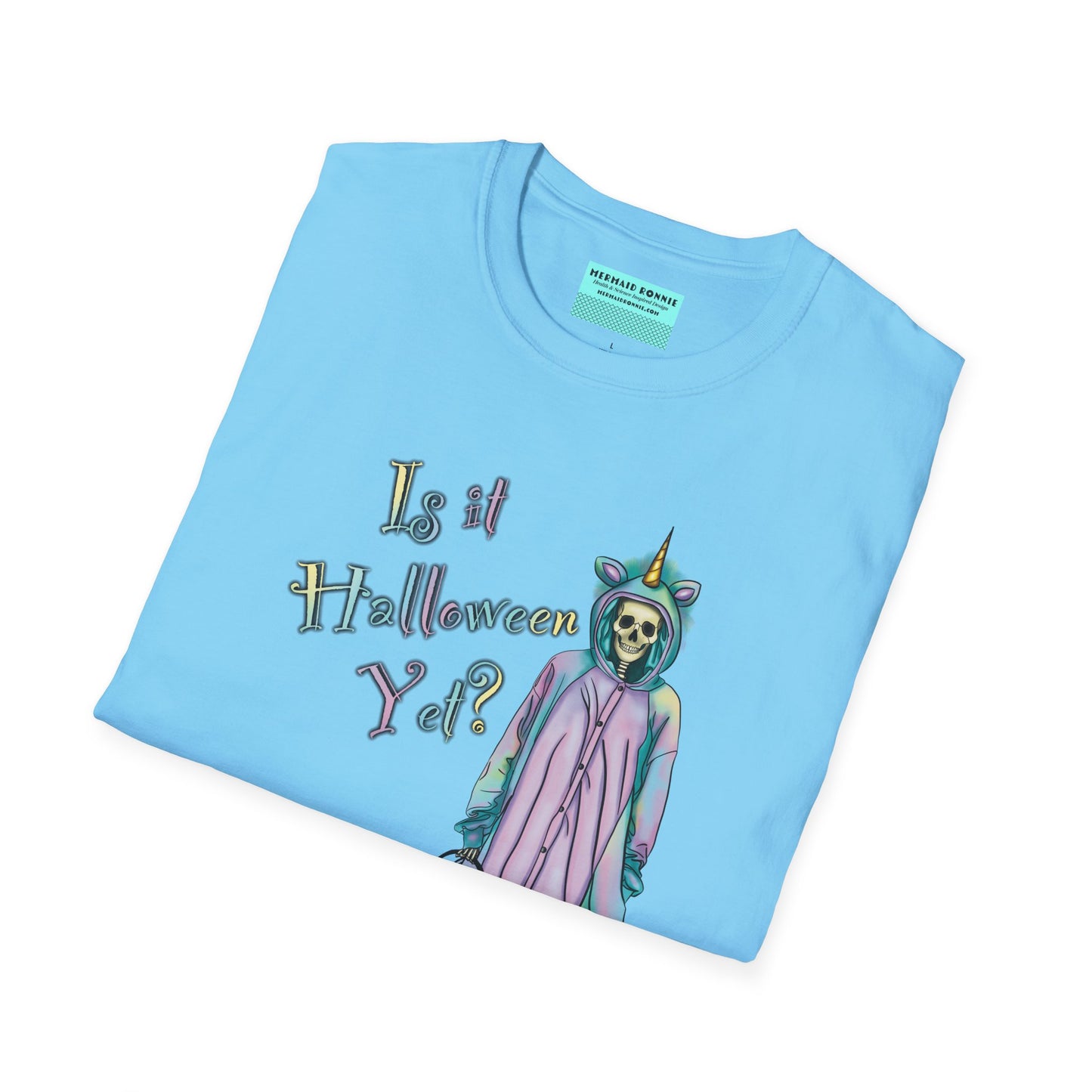 Folded blue t-shirt featuring a drawing of a skeleton in a unicorn costume onesie, with the phrase 'Is it Halloween yet?' printed on it.