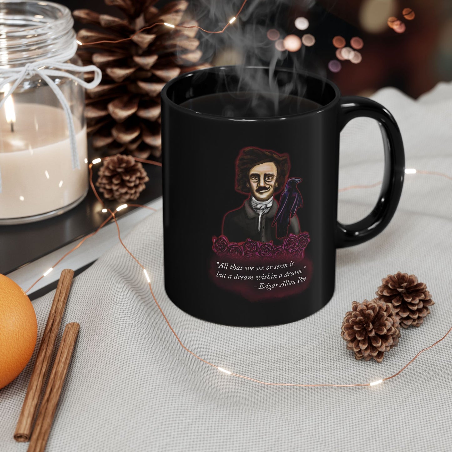 Right view of a small black coffee mug featuring a drawing of Edgar Allan Poe alongside a raven and deep red roses, with one of his famous quotes printed on the side. The mug is steaming and setting next to pine cones and sticks of cinnamon.