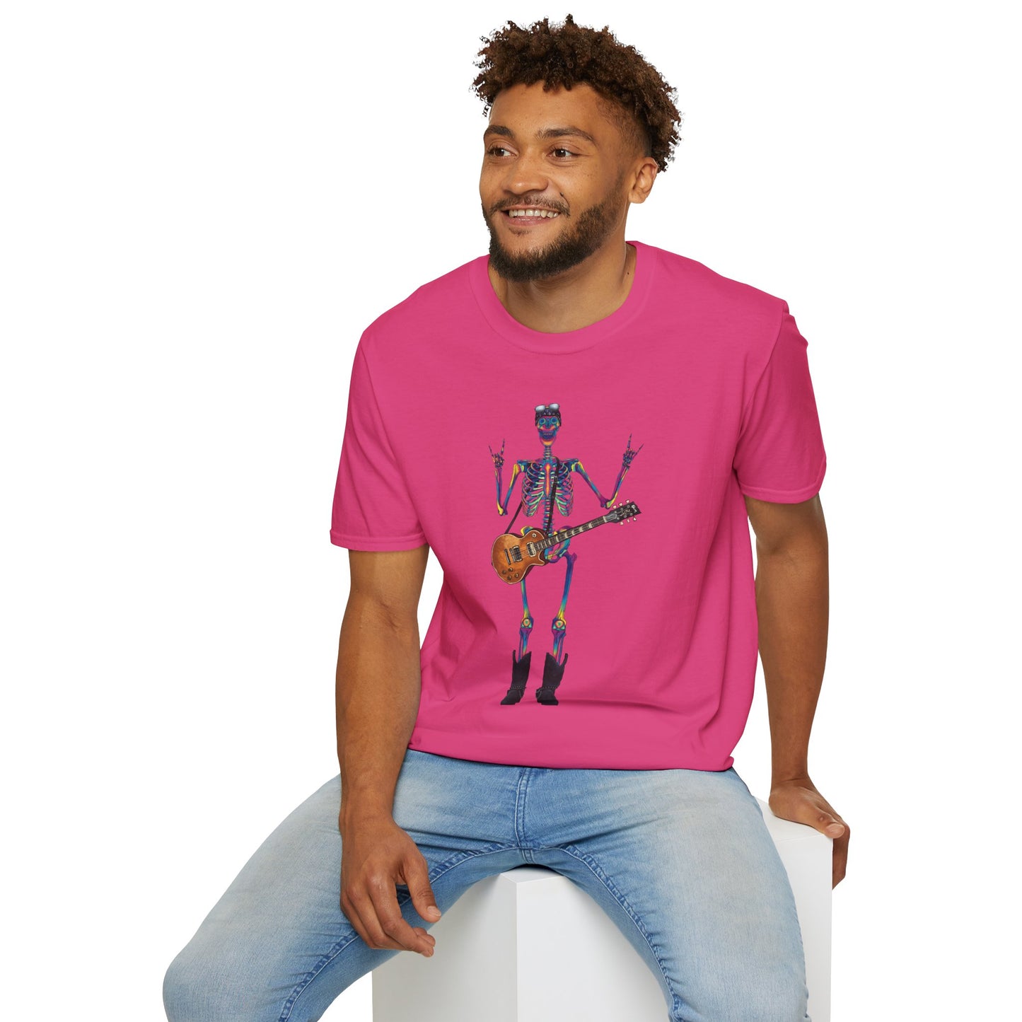 Man wearing a pink t-shirt featuring a tie-dye skeleton holding a guitar, dressed like a classic rocker with boots, a bandana, and rock-style clothing.
