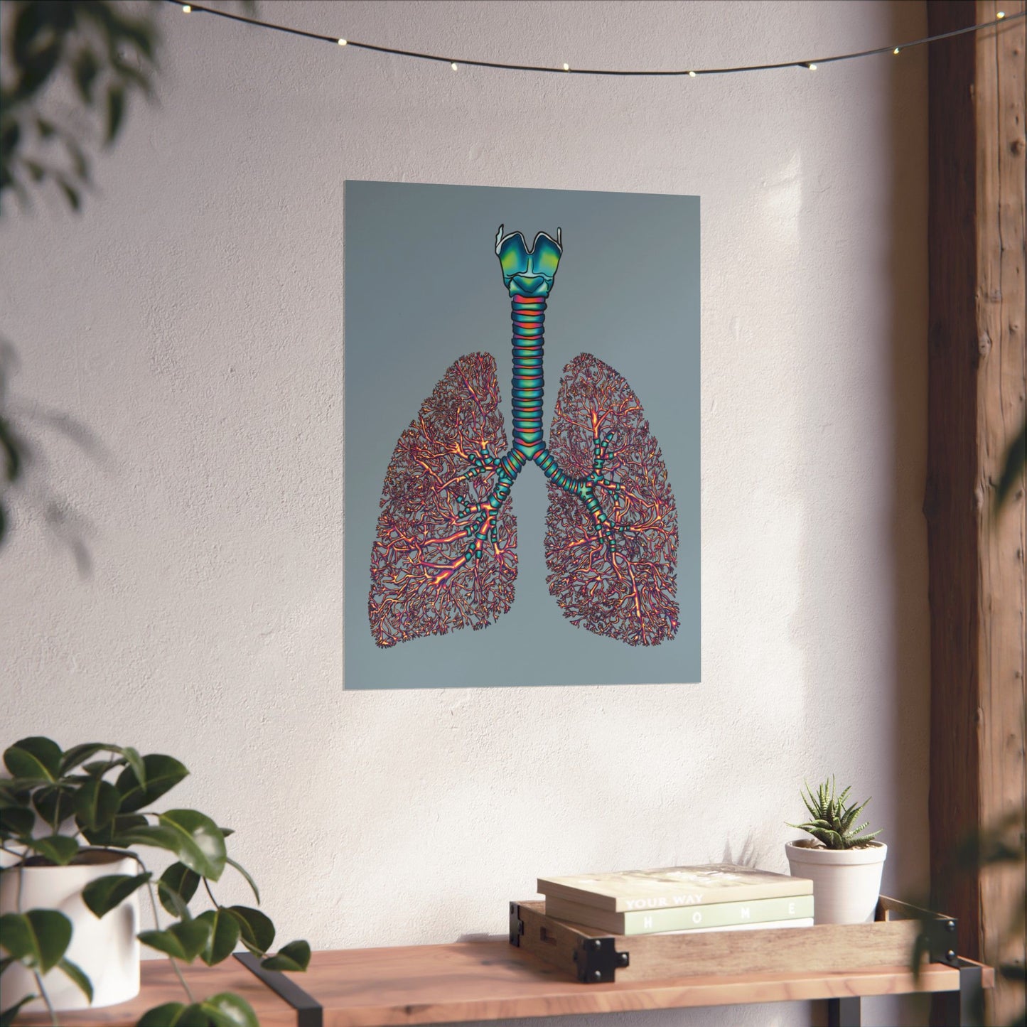 Large anatomical lungs poster hanging in a home, showing detailed illustrations of the bronchial tree, trachea, and larynx on a blue-grey background.