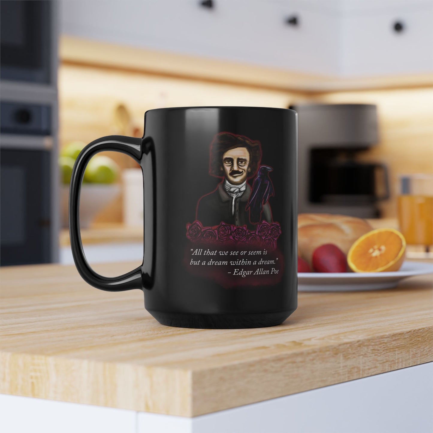 Left view of a large black coffee mug featuring a drawing of Edgar Allan Poe alongside a raven and deep red roses, with one of his famous quotes printed on the side. The mug is sitting on a kitchen counter near food.