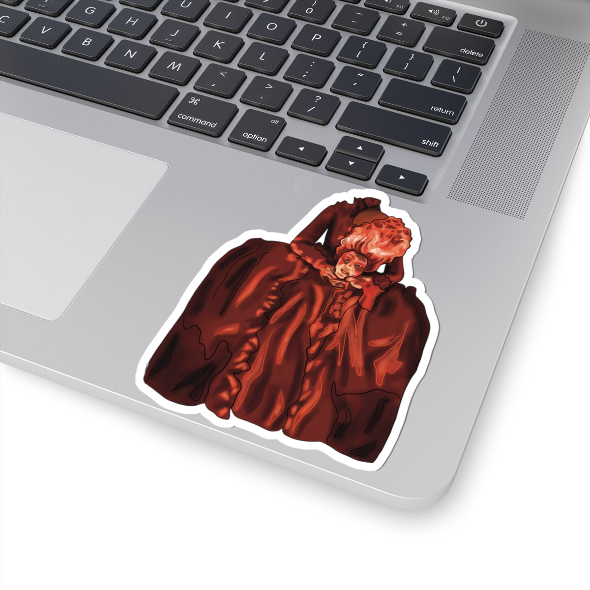 Large sticker on a computer featuring a drawing of Marie Antoinette dressed in red, holding her own head after beheading.