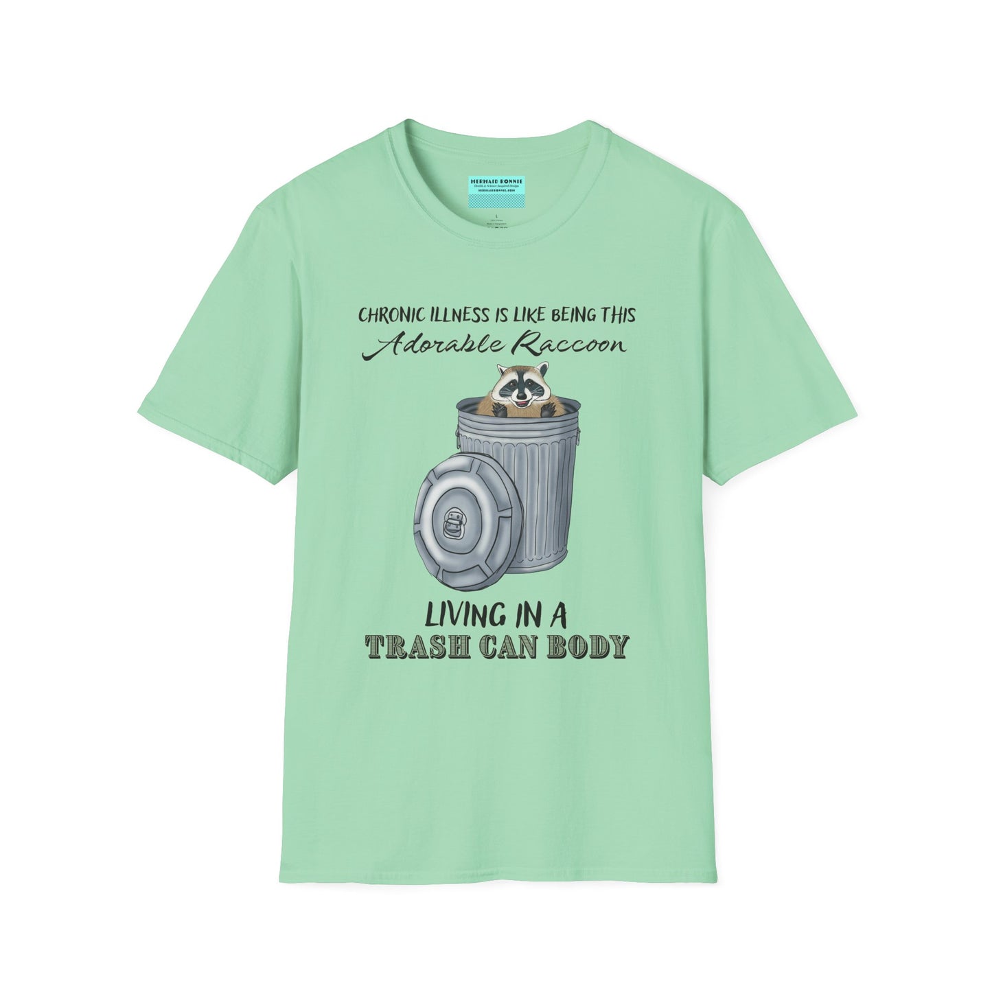 Mint green t-shirt featuring an illustration of a raccoon in a metal trash can, with the phrase 'Chronic illness is like being this adorable raccoon living in a trash can body' printed on it.