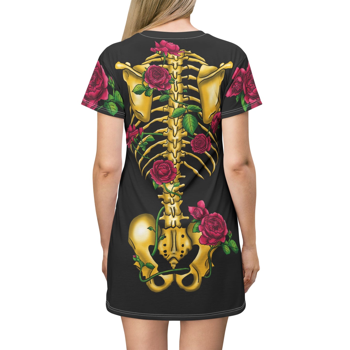 Posterior view of a woman wearing a black t-shirt dress featuring a gold anatomical illustration of the human skeleton on the back, adorned with blooming pink roses interwoven through the bones.