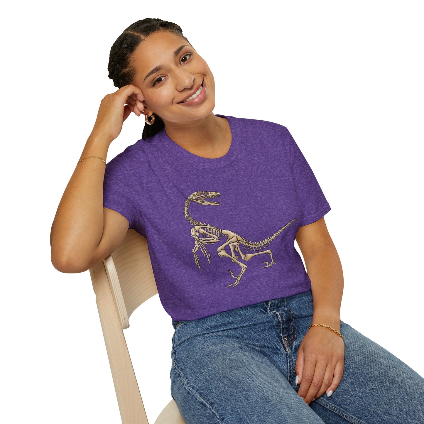 Woman wearing a purple unisex short sleeve t-shirt with a fierce velociraptor skeleton strutting across the chest—because who says extinct can’t be stylish?