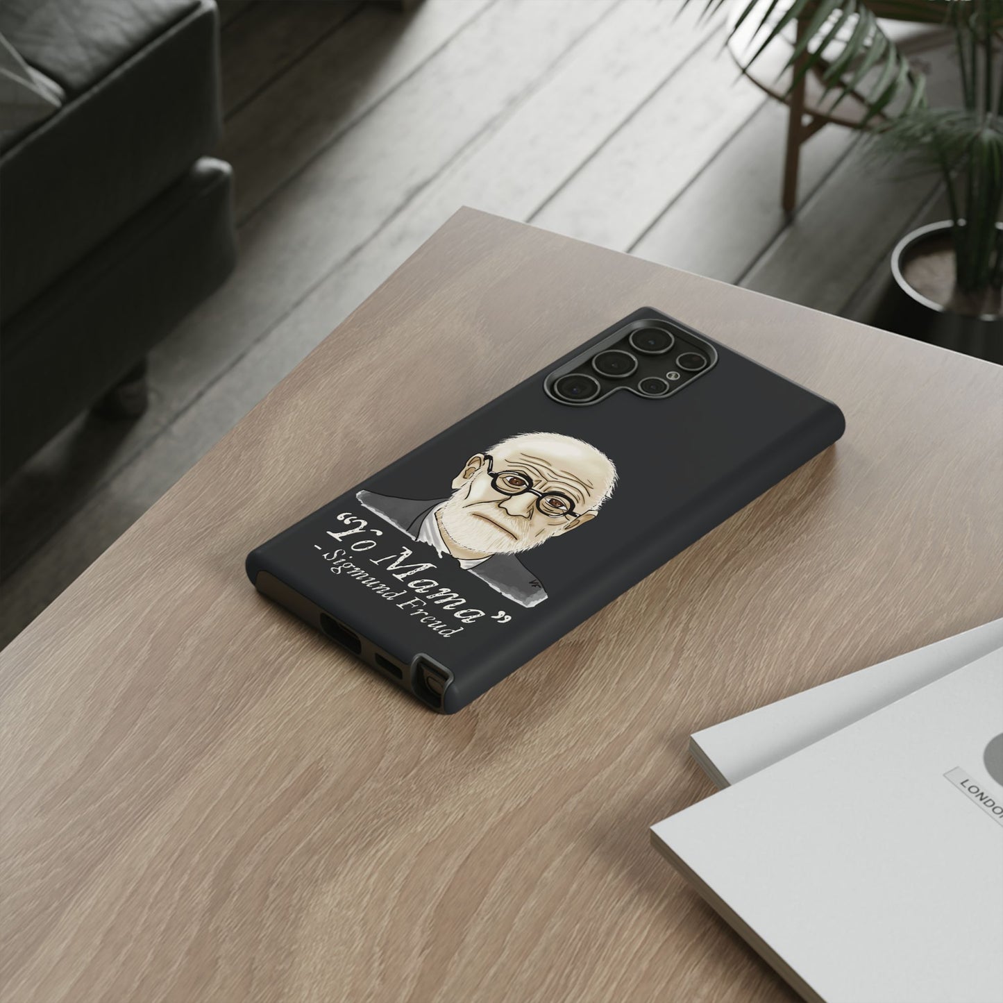 Dark grey phone case featuring a portrait of Sigmund Freud, paired with the cheeky quote “yo mama”—because even the father of psychoanalysis had mommy issues. The case is shown here in use, on a phone resting on a table.