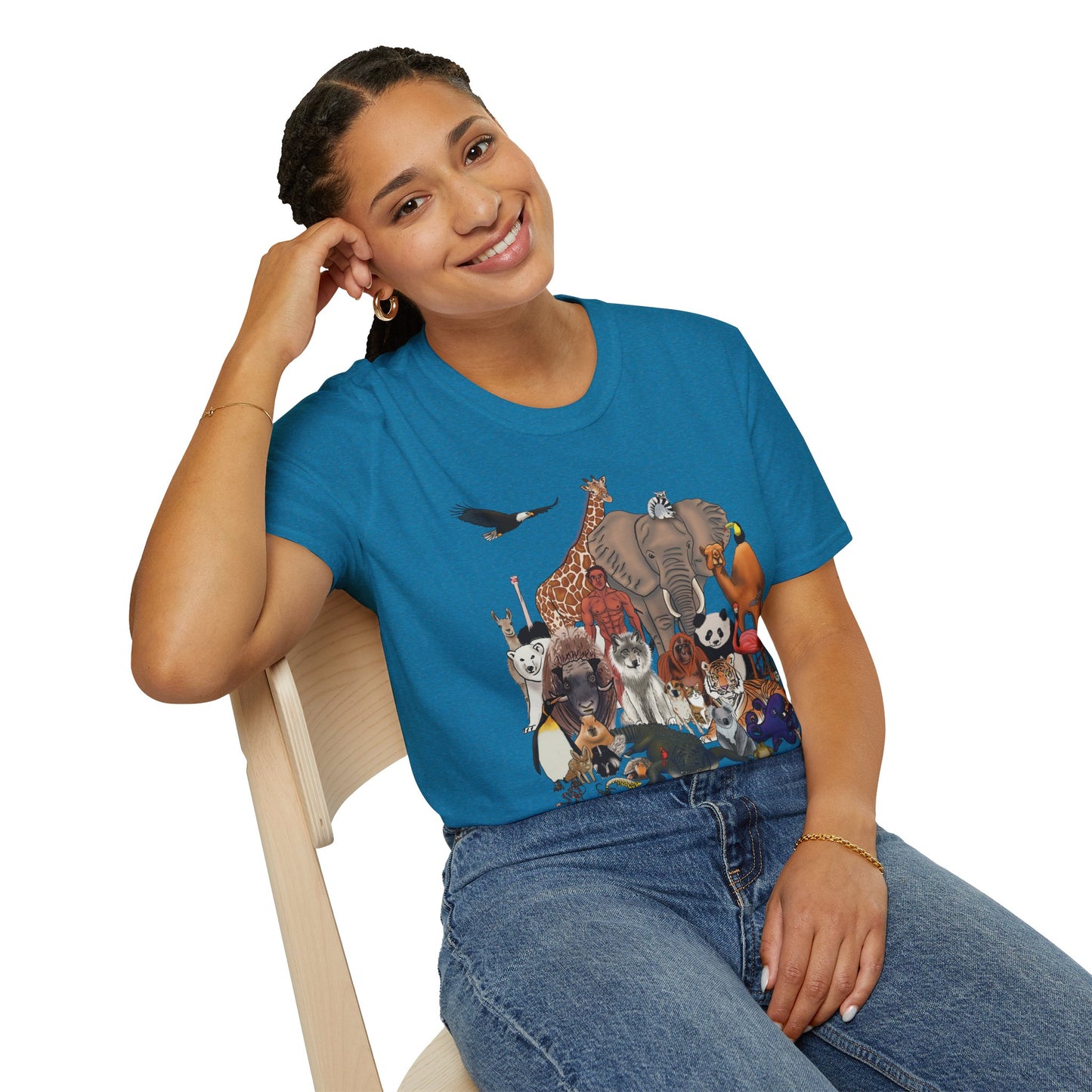 Woman wearing a blue unisex short sleeve tee featuring a diverse group of illustrated animals—like an elephant, bird, cat, and more—gathered around a human in the center. Below the image, the text reads "humans are animals too," celebrating our place in the animal kingdom with a touch of humor and humility.