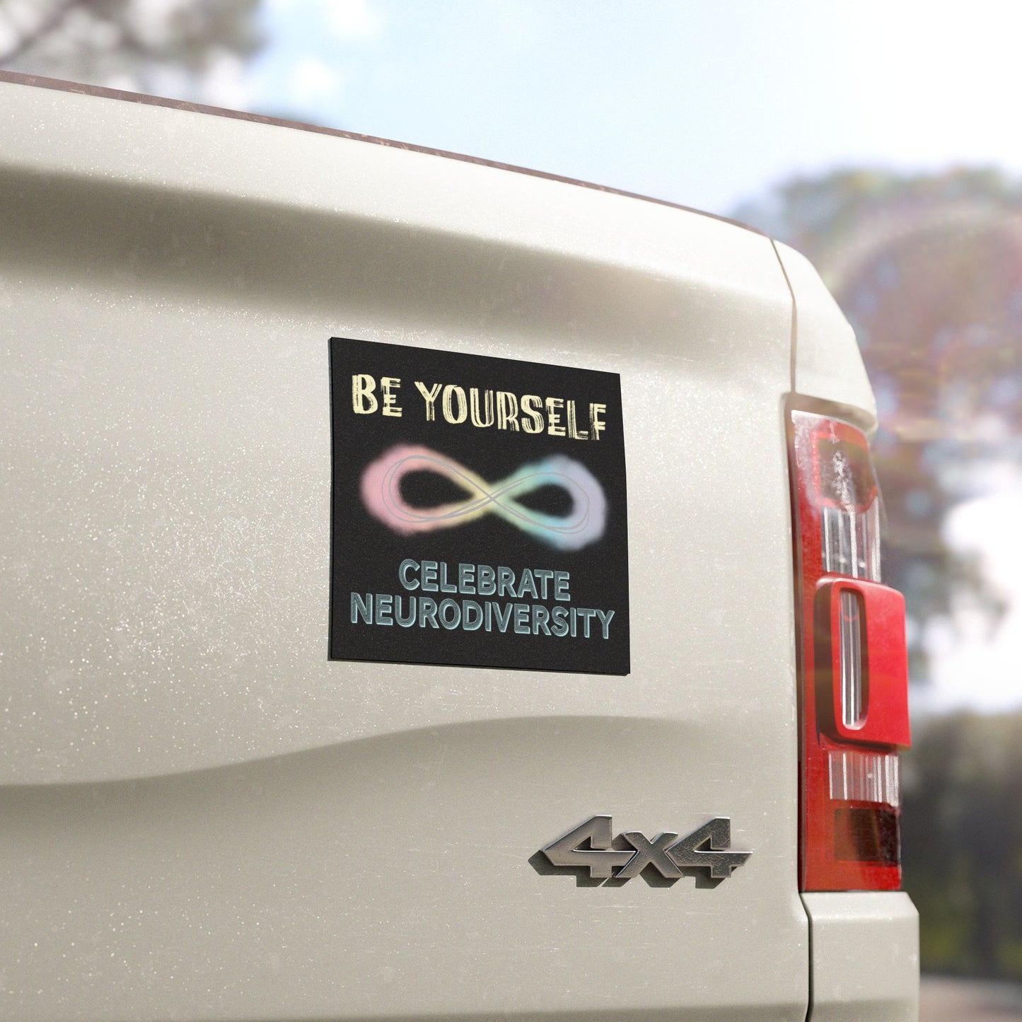 Close up view of a black magnet on a pick-up truck with a pastel-colored infinity symbol and text that reads 'Be yourself, celebrate neurodiversity.'