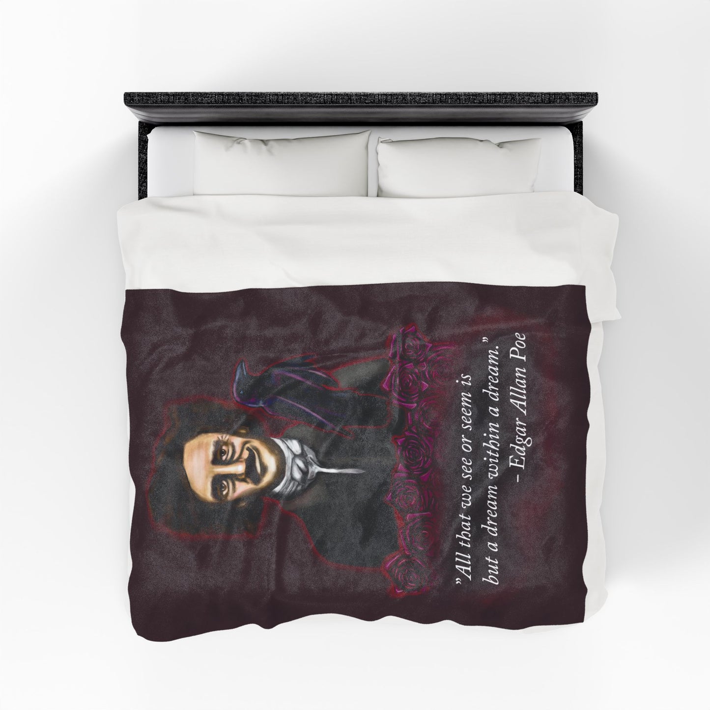 A large burgundy velveteen plush blanket featuring a smirking Edgar Allan Poe, a brooding raven, and crimson roses—perfect for cozying up with your favorite haunting thoughts and the poetic quote, "All that we see or seem is but a dream within a dream. Shown on a queen size bed from above.