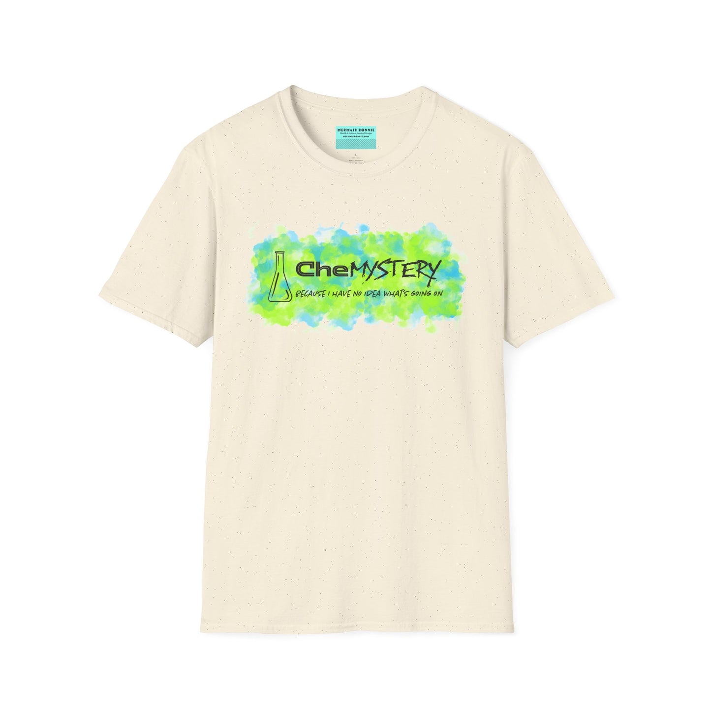 Beige short-sleeve unisex t-shirt with playful watercolor-style blue and green splotches, a simple line-drawn beaker, and the witty phrase “CheMystery: because I have no idea what’s going on”—perfect for anyone who’s ever been personally victimized by the periodic table.