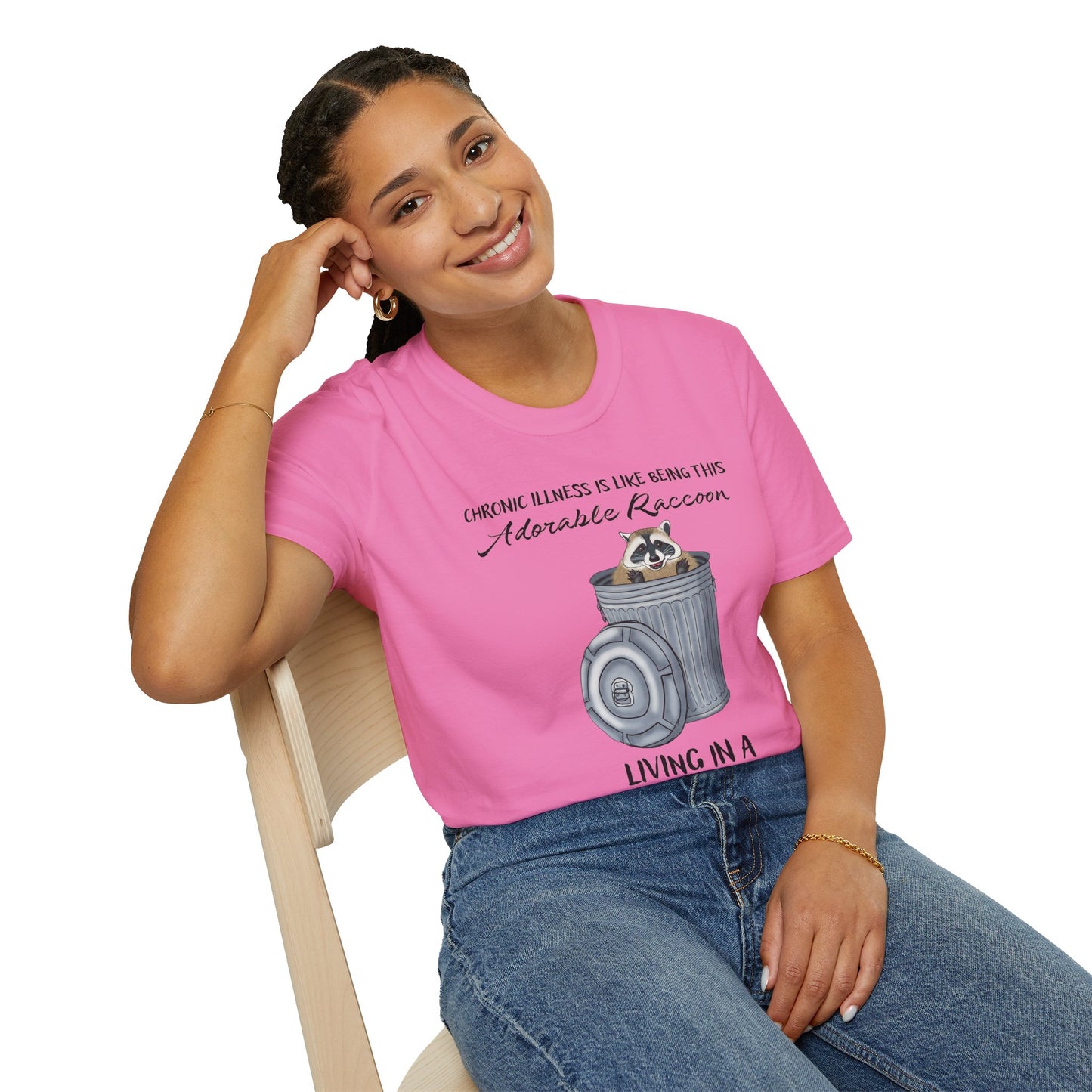 Woman wearing a pink t-shirt featuring a picture of a raccoon in a metal trash can, with the phrase 'Chronic illness is like being this adorable raccoon living in a trash can body' printed on it.