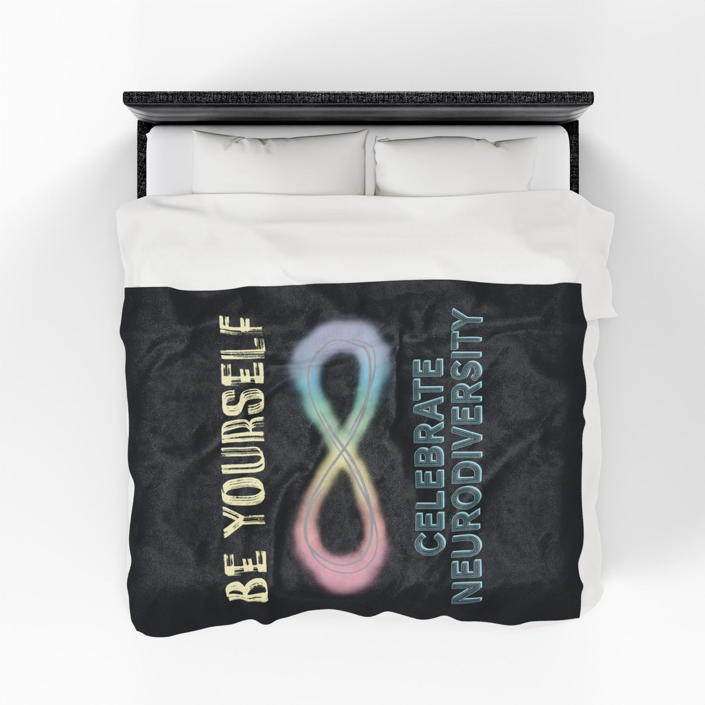 A large black velveteen plush blanket with a pastel rainbow infinity symbol and the uplifting phrase "Be yourself, celebrate neurodiversity"—soft enough to soothe your senses, bold enough to make a statement. Shown on a queen size bed.
