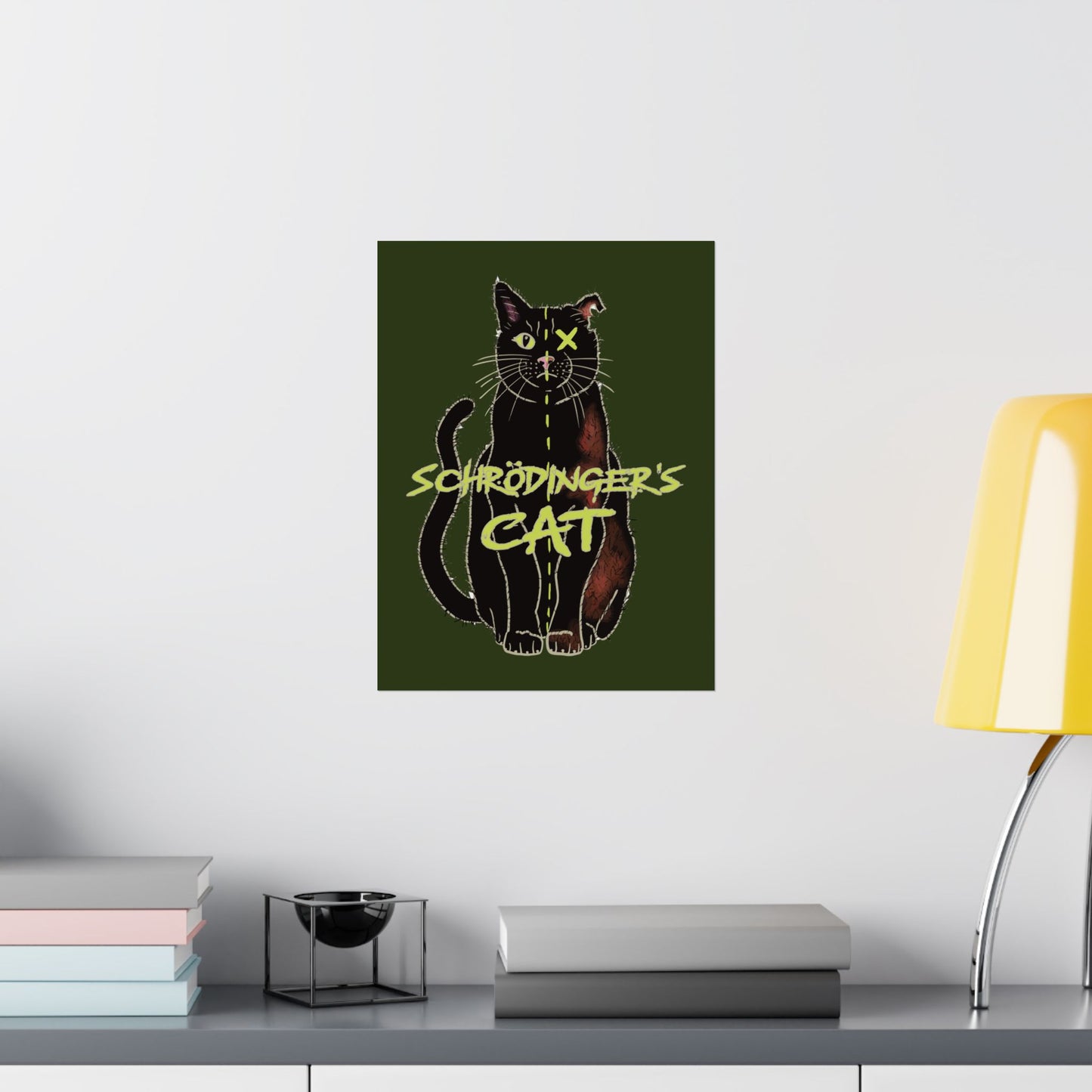 A medium thought-provoking Schrödinger's Cat poster set against a dark green background, featuring a black cat split down the middle—half alive, half dead. The phrase “Schrödinger's Cat” sits boldly across the image, capturing the paradox of quantum physics with a dash of feline mystery. It is shown here hung in an office setting.