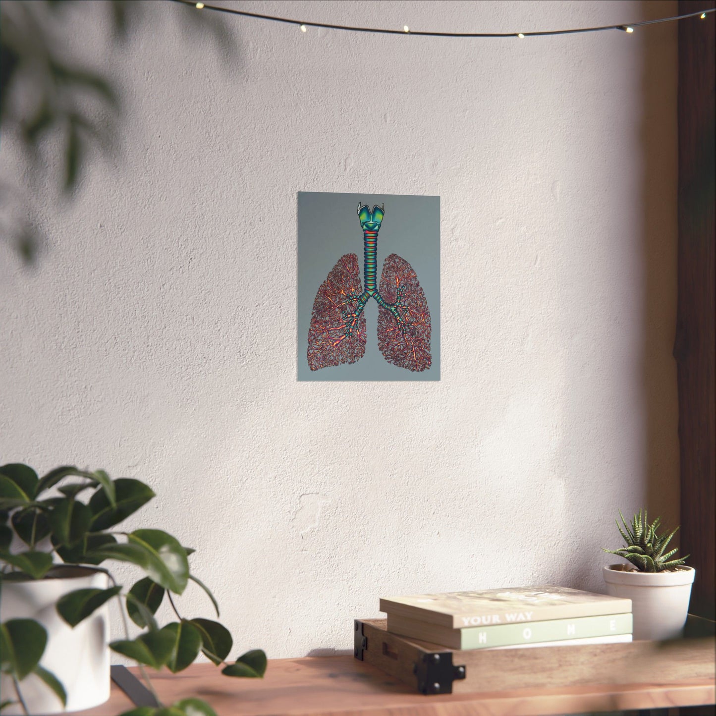 Small anatomical lungs poster hanging in a home, showing detailed illustrations of the bronchial tree, trachea, and larynx on a blue-grey background.