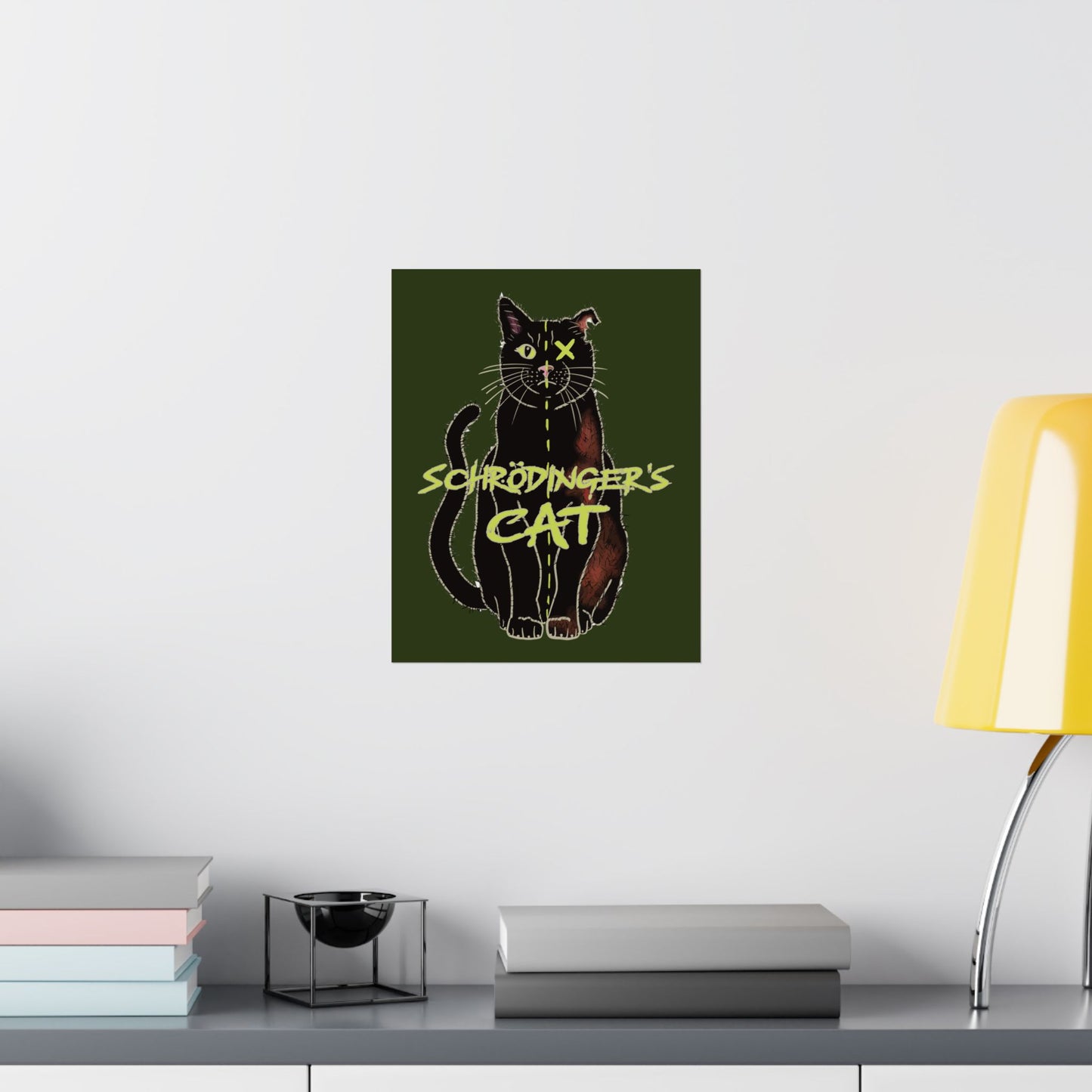 A small thought-provoking Schrödinger's Cat poster set against a dark green background, featuring a black cat split down the middle—half alive, half dead. The phrase “Schrödinger's Cat” sits boldly across the image, capturing the paradox of quantum physics with a dash of feline mystery. It is shown here hung in an office setting.