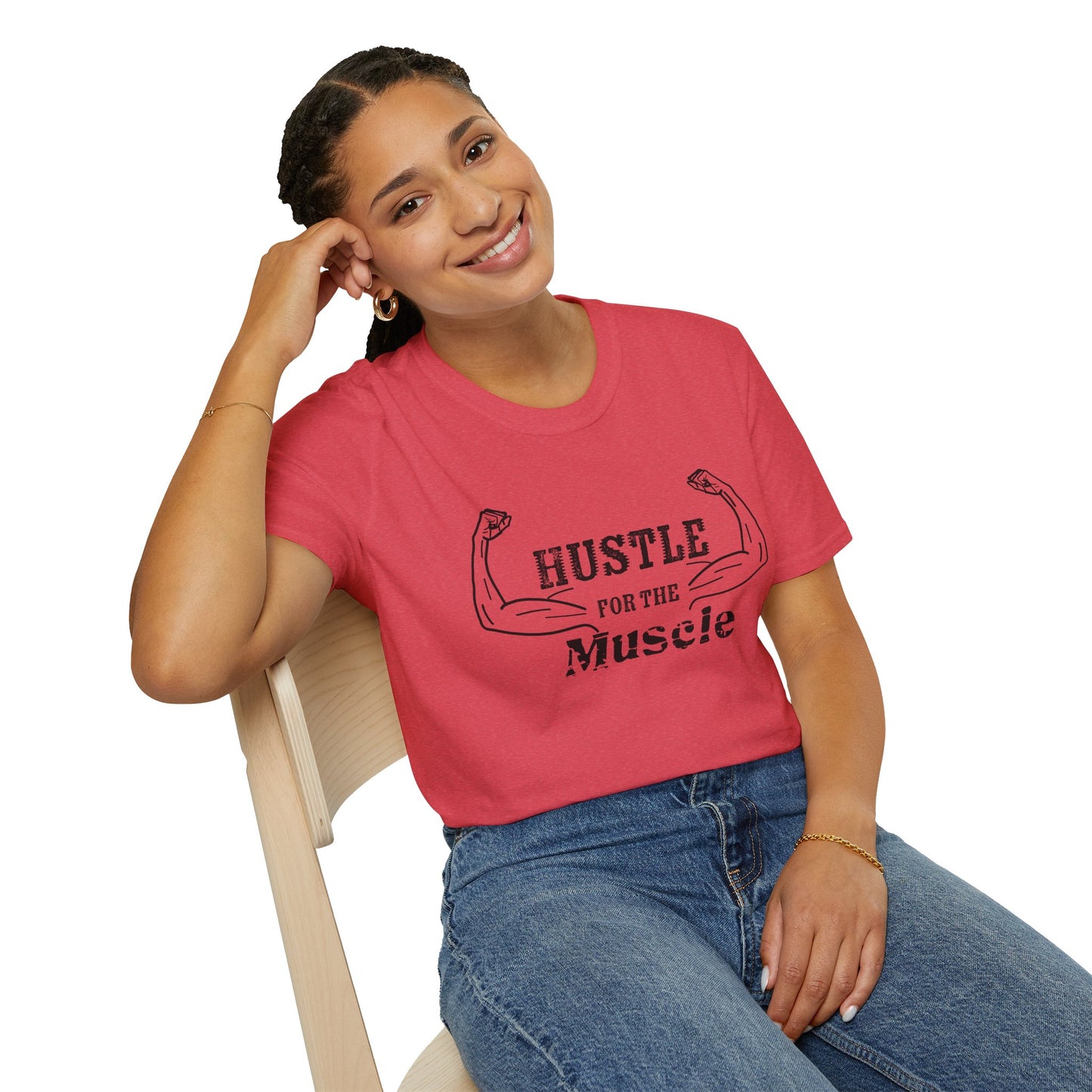 Woman wearing a red unisex short sleeve t-shirt with a bold graphic of strong, flexed feminine arms and the empowering phrase "Hustle for the Muscle"—because strength is stylish and lifting is for everyone.