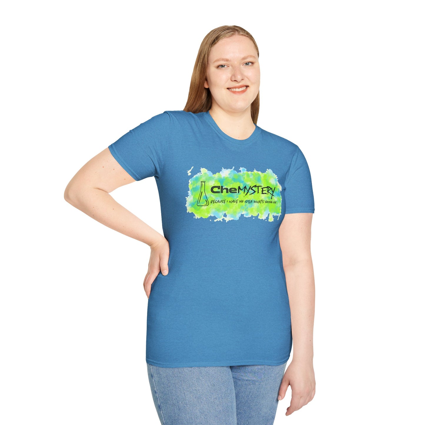 Woman wearing a blue short-sleeve unisex t-shirt with playful watercolor-style blue and green splotches, a simple line-drawn beaker, and the witty phrase “CheMystery: because I have no idea what’s going on”—perfect for anyone who’s ever been personally victimized by the periodic table.