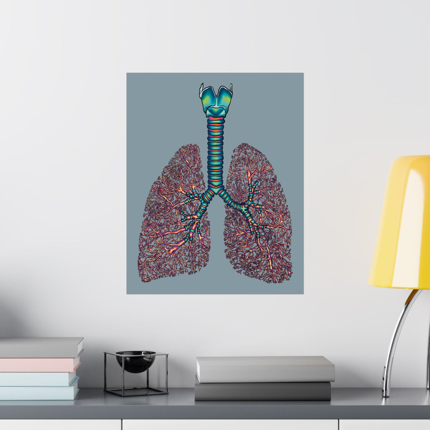 Medium anatomical lungs poster hanging in an office, showing detailed illustrations of the bronchial tree, trachea, and larynx on a blue-grey background.
