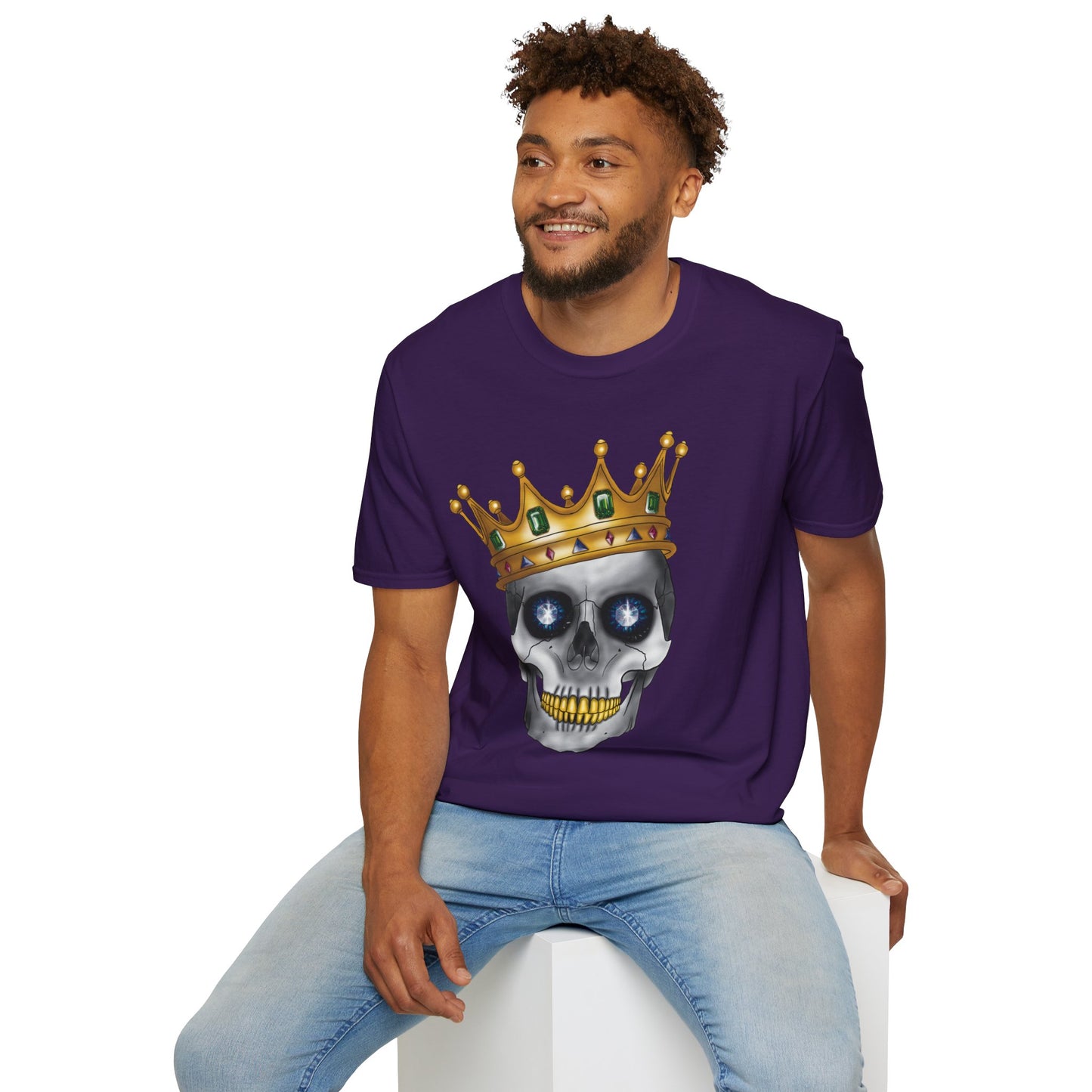 Man wearing a purple t-shirt featuring an anatomical skull wearing an ornate crown, with gold teeth, large sapphire gemstones in the eye sockets, and emeralds and rubies decorating the crown.