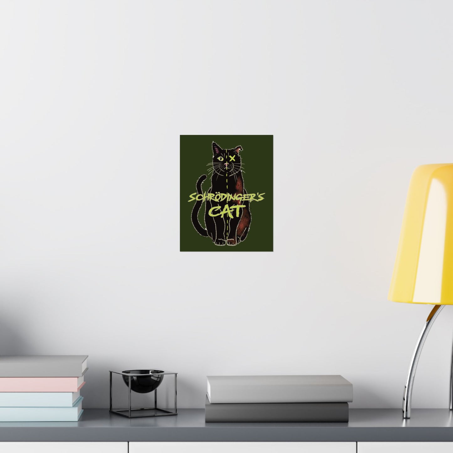 An extra-small thought-provoking Schrödinger's Cat poster set against a dark green background, featuring a black cat split down the middle—half alive, half dead. The phrase “Schrödinger's Cat” sits boldly across the image, capturing the paradox of quantum physics with a dash of feline mystery. It is shown here hung in an office setting.