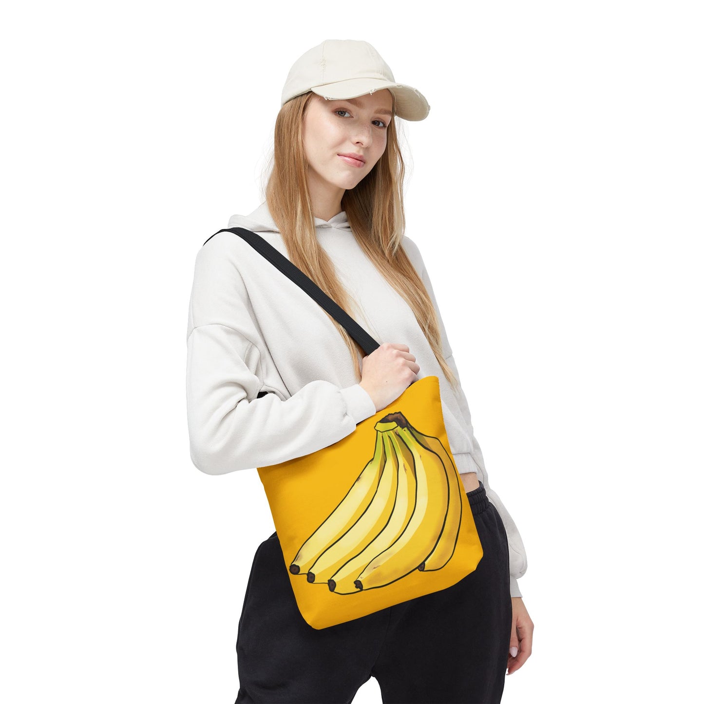 Woman carrying small yellow tote bag featuring a playful illustration of a bunch of bananas on the front, set against a solid yellow background.