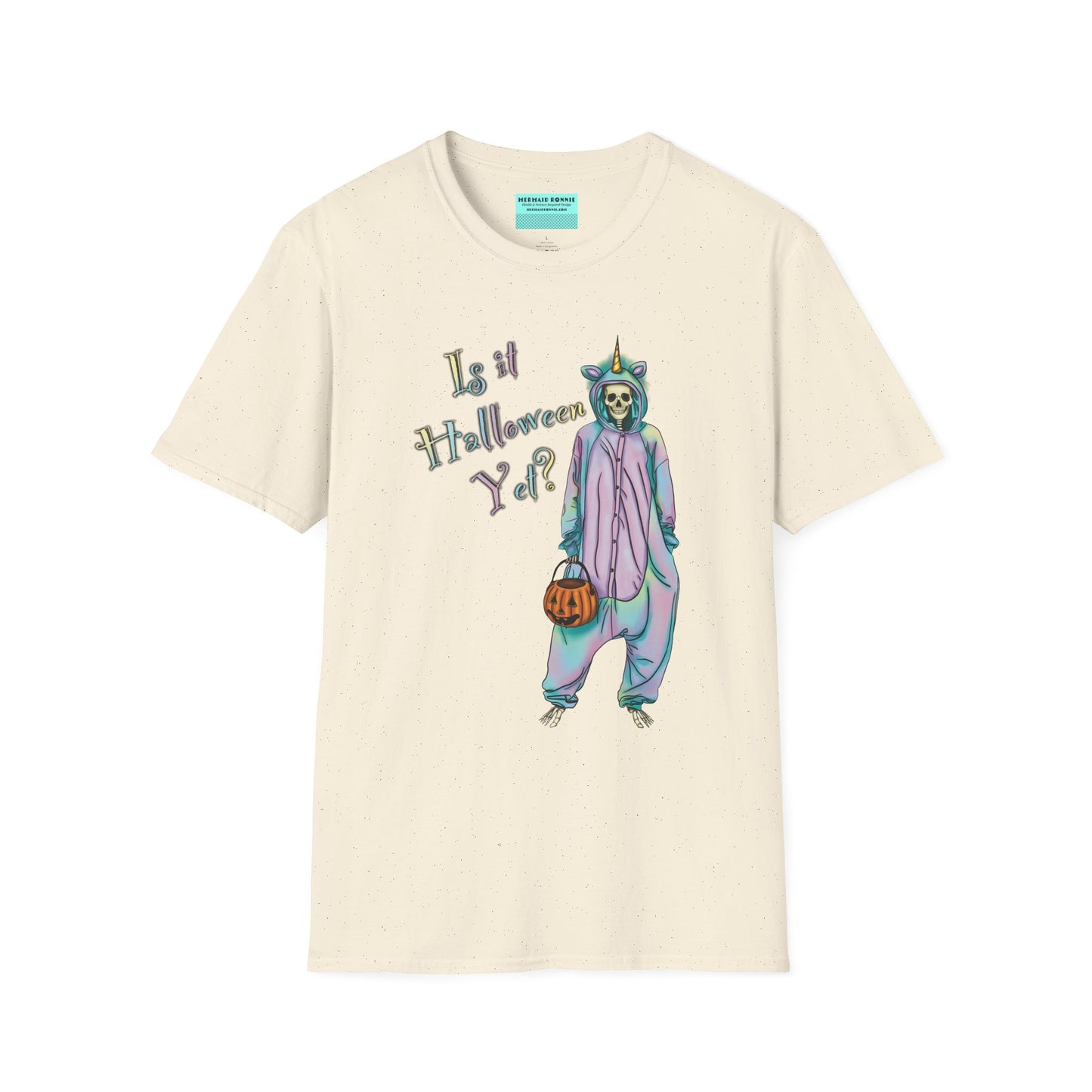 Beige t-shirt featuring a drawing of a skeleton in a unicorn costume onesie, with the phrase 'Is it Halloween yet?' printed on it.