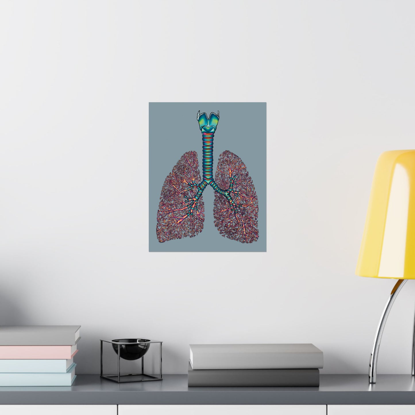 Medium poster displayed on a wall in an office setting, featuring an illustration of anatomical lungs with detailed bronchial tree, trachea, and larynx, set against a blue-grey background.