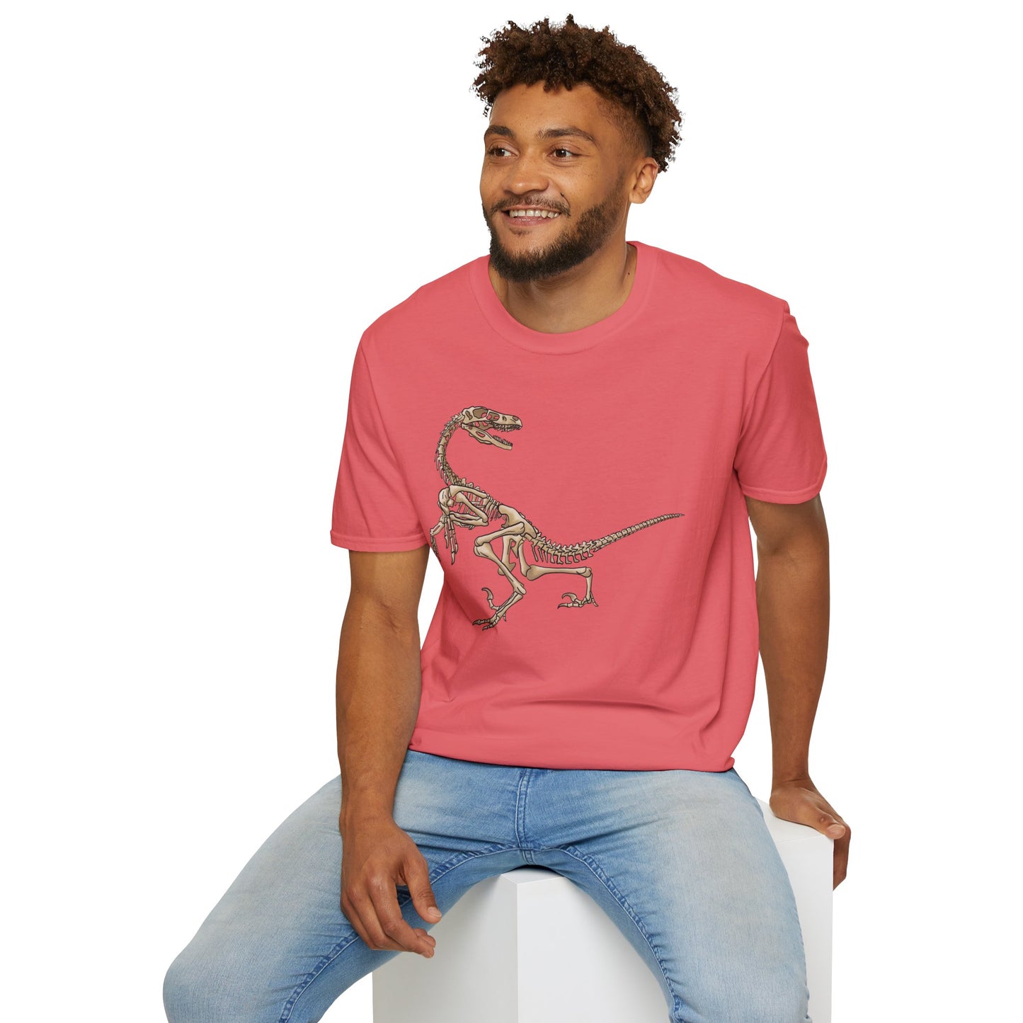 Man wearing a coral unisex short sleeve t-shirt with a fierce velociraptor skeleton strutting across the chest—because who says extinct can’t be stylish?