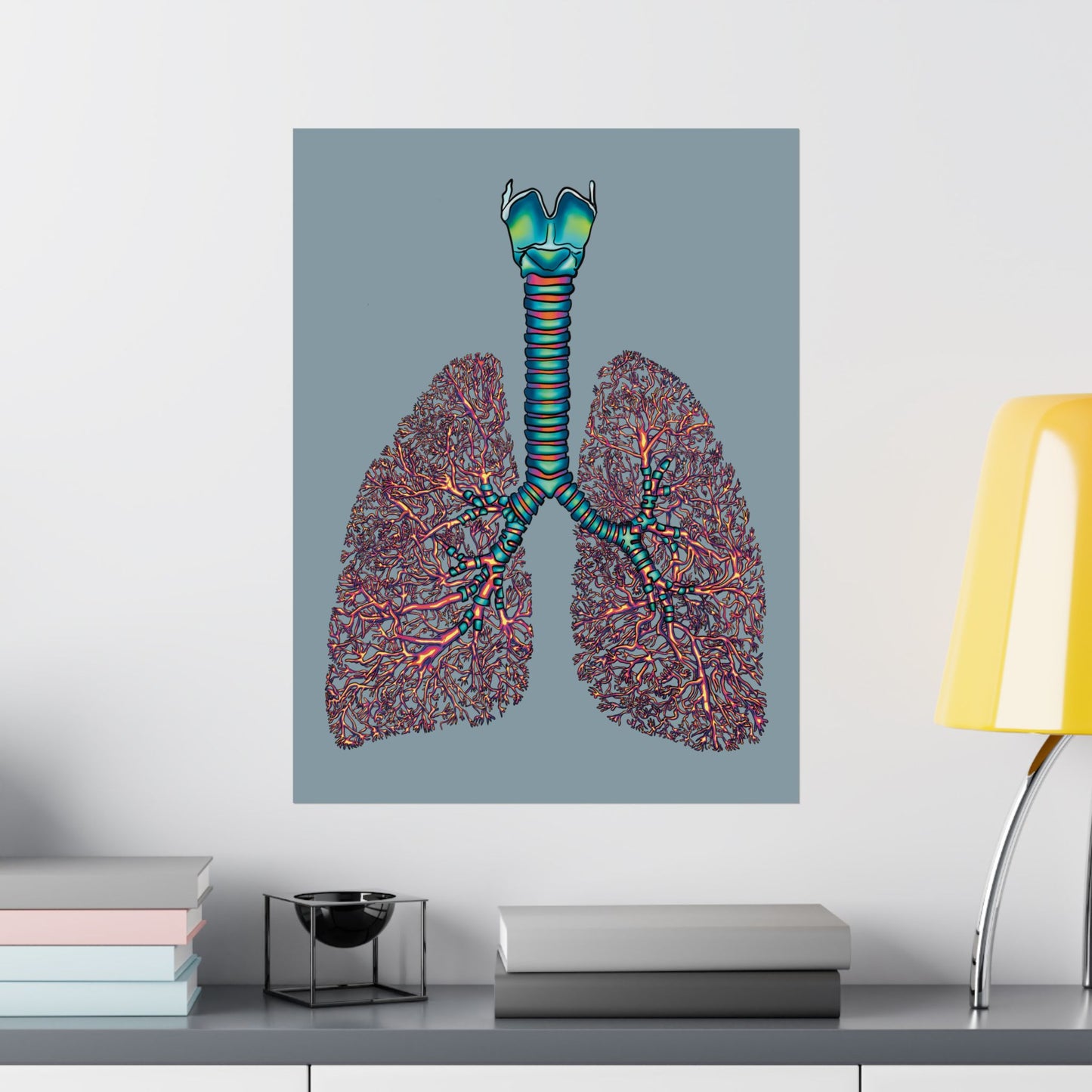 Large poster displayed on a wall in an office setting, featuring an illustration of anatomical lungs with detailed bronchial tree, trachea, and larynx, set against a blue-grey background.