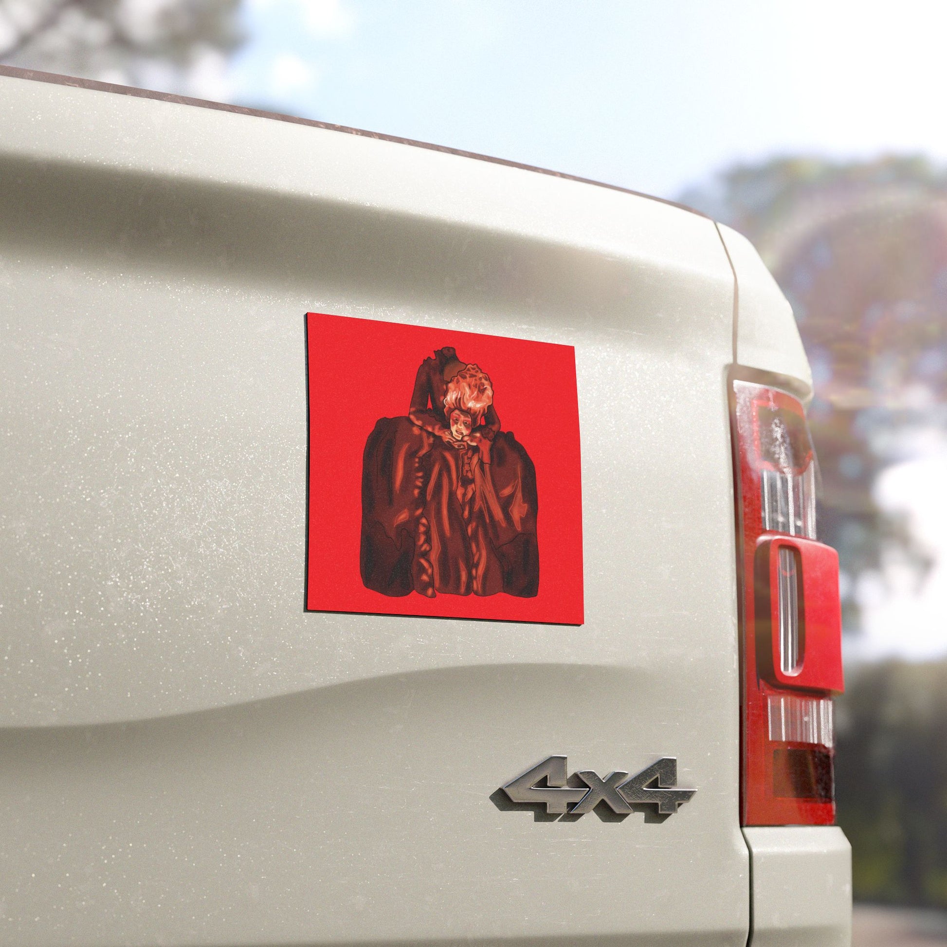 Close view of a magnet on the back of a truck with an illustration of a beheaded Marie Antoinette holding her head, set against a red background.
