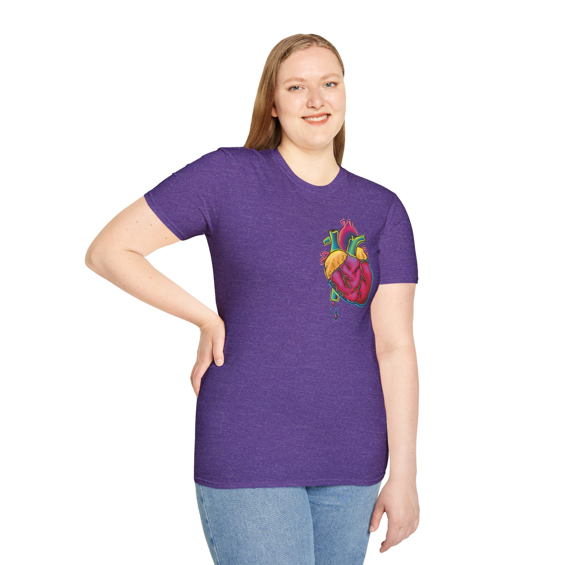 Woman wearing a purple unisex short sleeve t-shirt featuring a bold neon anatomical heart front and off-center, complete with dripping blood vessels—because nothing says “wear your heart on your sleeve” like wearing it smack on your chest in highlighter tones.
