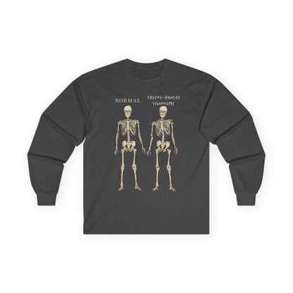 A grey long sleeve shirt with two skeletons side by side—one labeled "normal," the other "Ehlers-Danlos Syndrome"—visually showcasing the effects of EDS with a clever, anatomy-inspired twist.