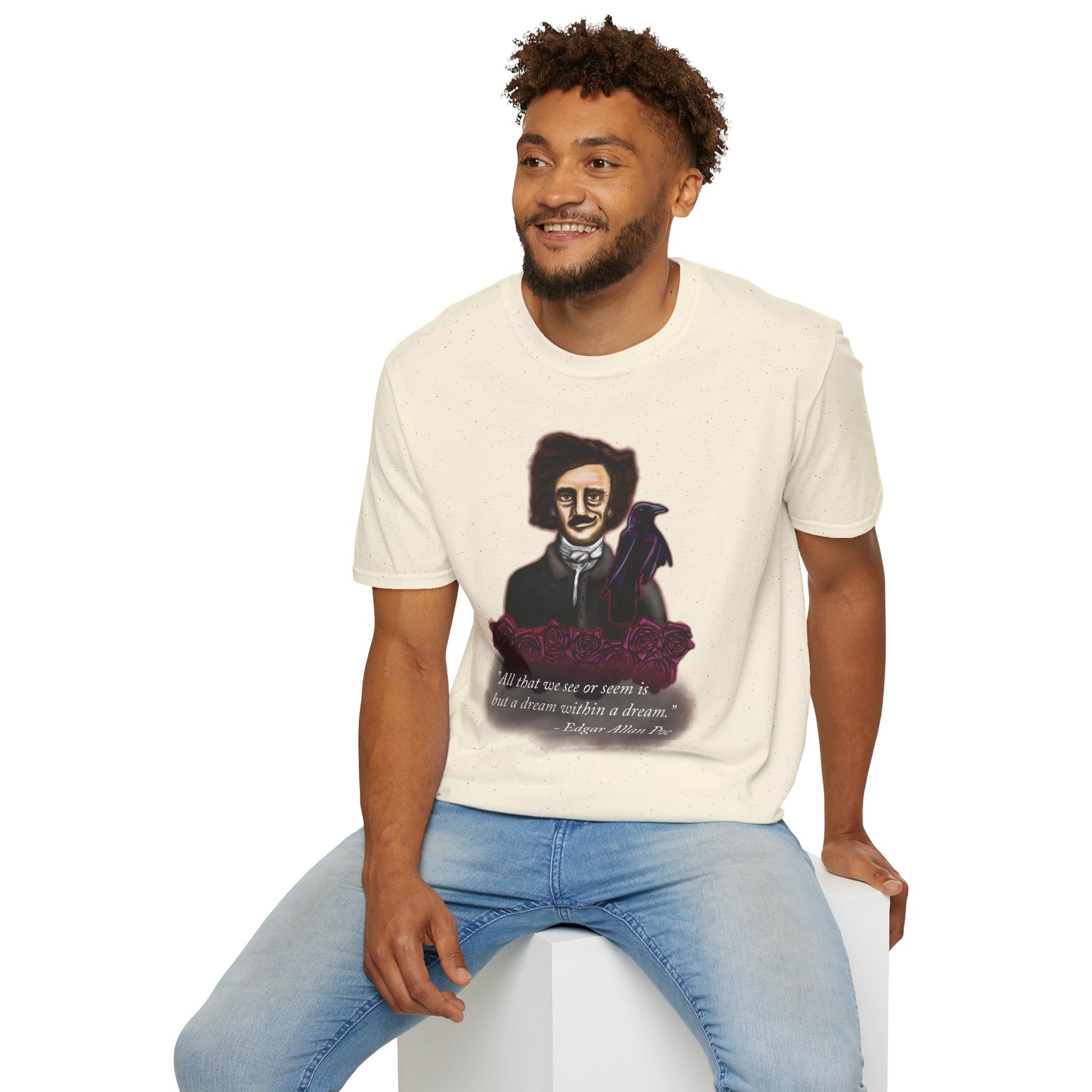 Man wearing a beige t-shirt featuring a drawing of Edgar Allan Poe with a raven perched nearby and red roses surrounding them, along with the quote 'All that we see or seem is but a dream within a dream.'