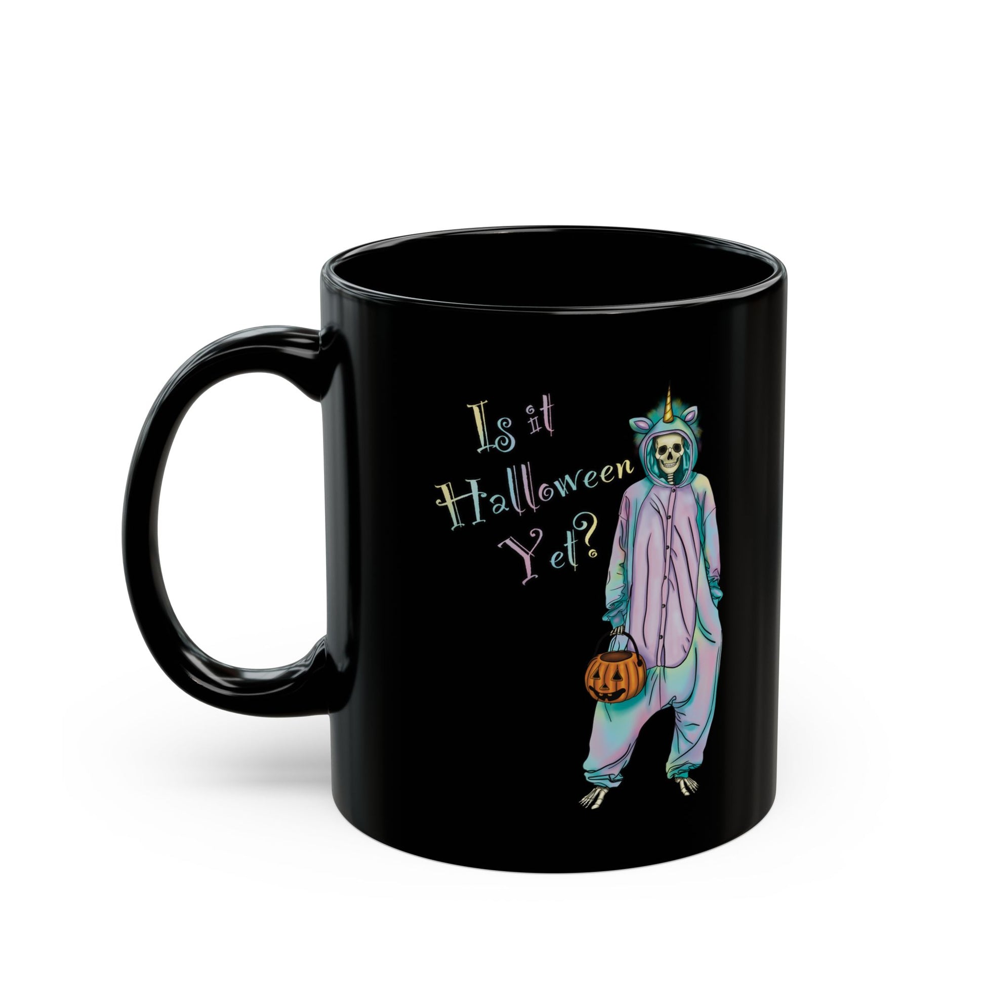 Left view of a small black coffee mug featuring a whimsical illustration of a skeleton dressed in a pastel unicorn onesie, complete with a horn and rainbow accents; the playful text reads "Is it Halloween yet?"—because spooky season should be year-round.