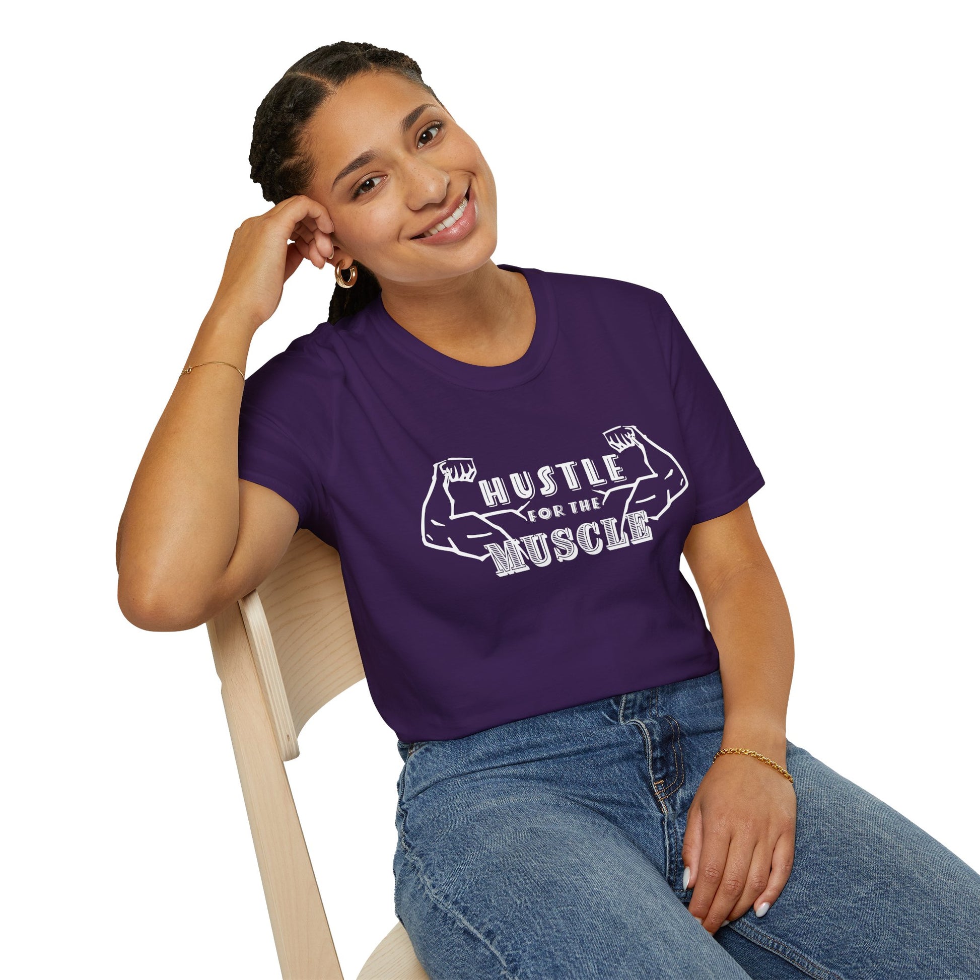 Woman wearing a dark purple unisex short sleeve t-shirt featuring a pair of flexed, muscle-bound arms and the bold text "Hustle for the Muscle"—because gains don’t come from wishes, they come from reps.