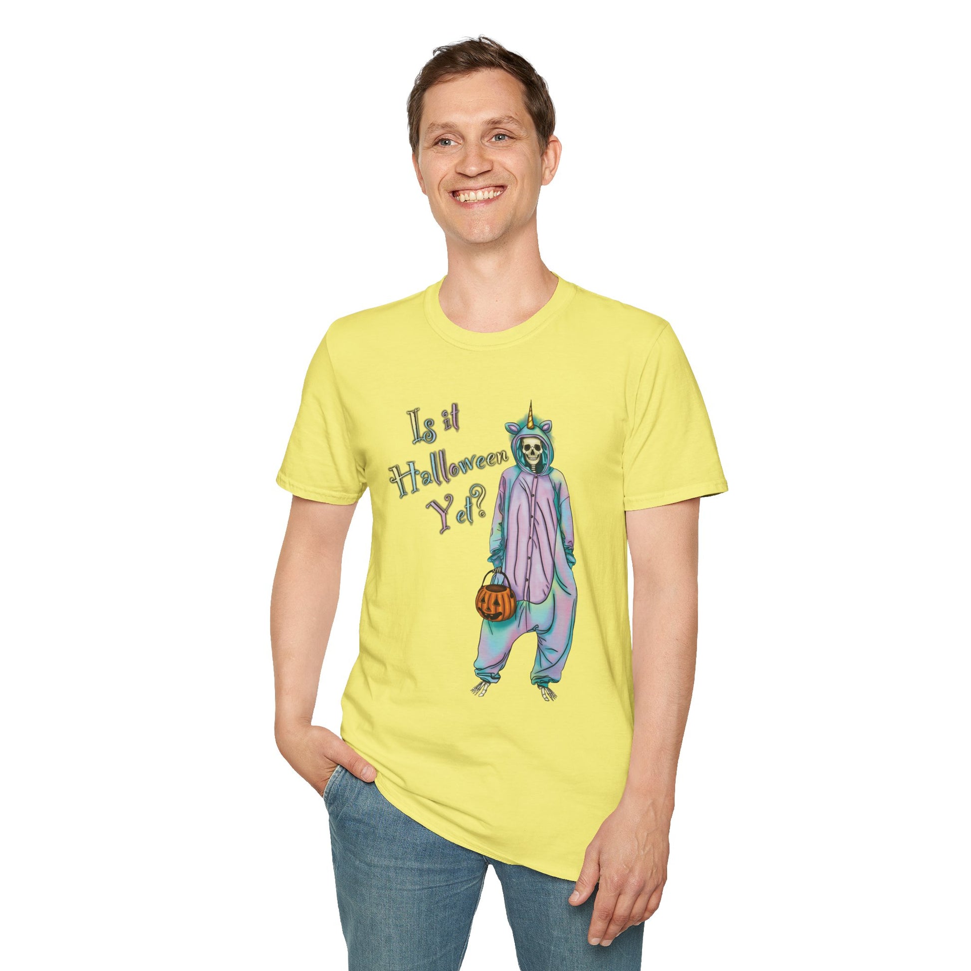 Man wearing a yellow t-shirt featuring a drawing of a skeleton in a unicorn costume onesie, with the phrase 'Is it Halloween yet?' printed on it.