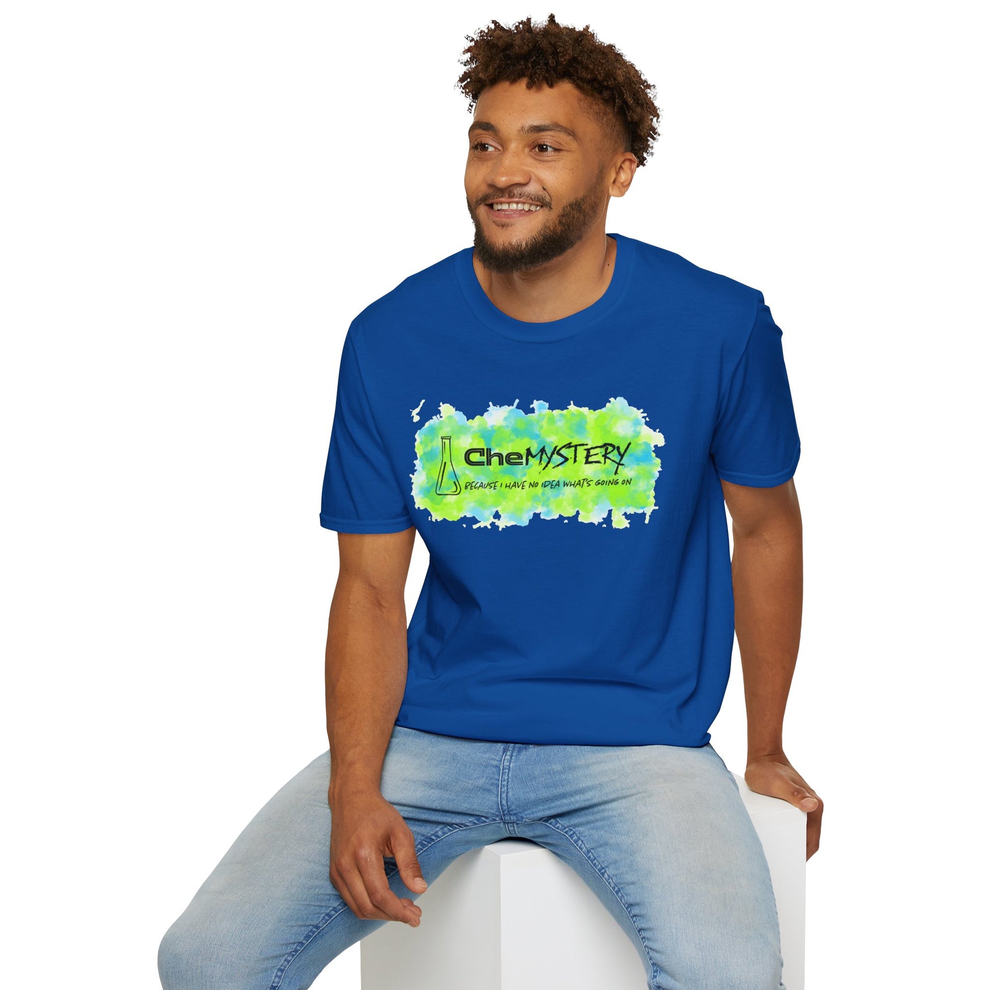 Man wearing a royal blue short-sleeve unisex t-shirt with playful watercolor-style blue and green splotches, a simple line-drawn beaker, and the witty phrase “CheMystery: because I have no idea what’s going on”—perfect for anyone who’s ever been personally victimized by the periodic table.
