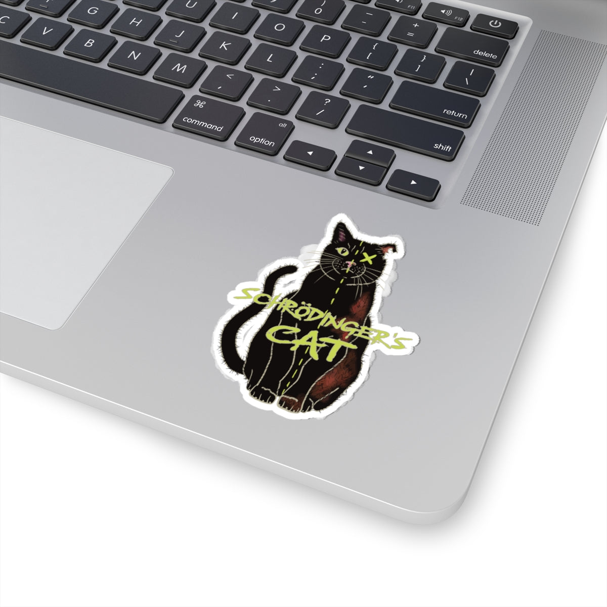 Small sticker adhered to computer featuring a black cat with one half depicted as alive and the other half as dead, with an X over one eye, representing Schrödinger's cat.