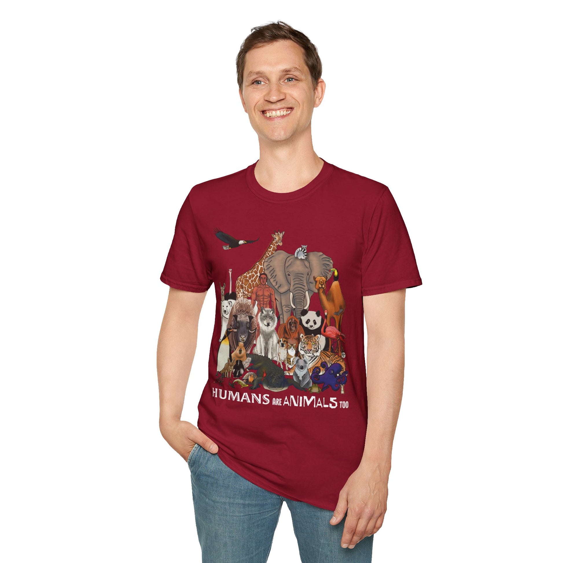 Man wearing a red unisex short sleeve tee featuring a diverse group of illustrated animals—like an elephant, bird, cat, and more—gathered around a human in the center. Below the image, the text reads "humans are animals too," celebrating our place in the animal kingdom with a touch of humor and humility.