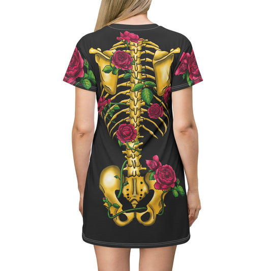 Posterior view of a woman wearing a black t-shirt dress featuring a gold anatomical illustration of the human skeleton on the back, adorned with blooming pink roses interwoven through the bones.