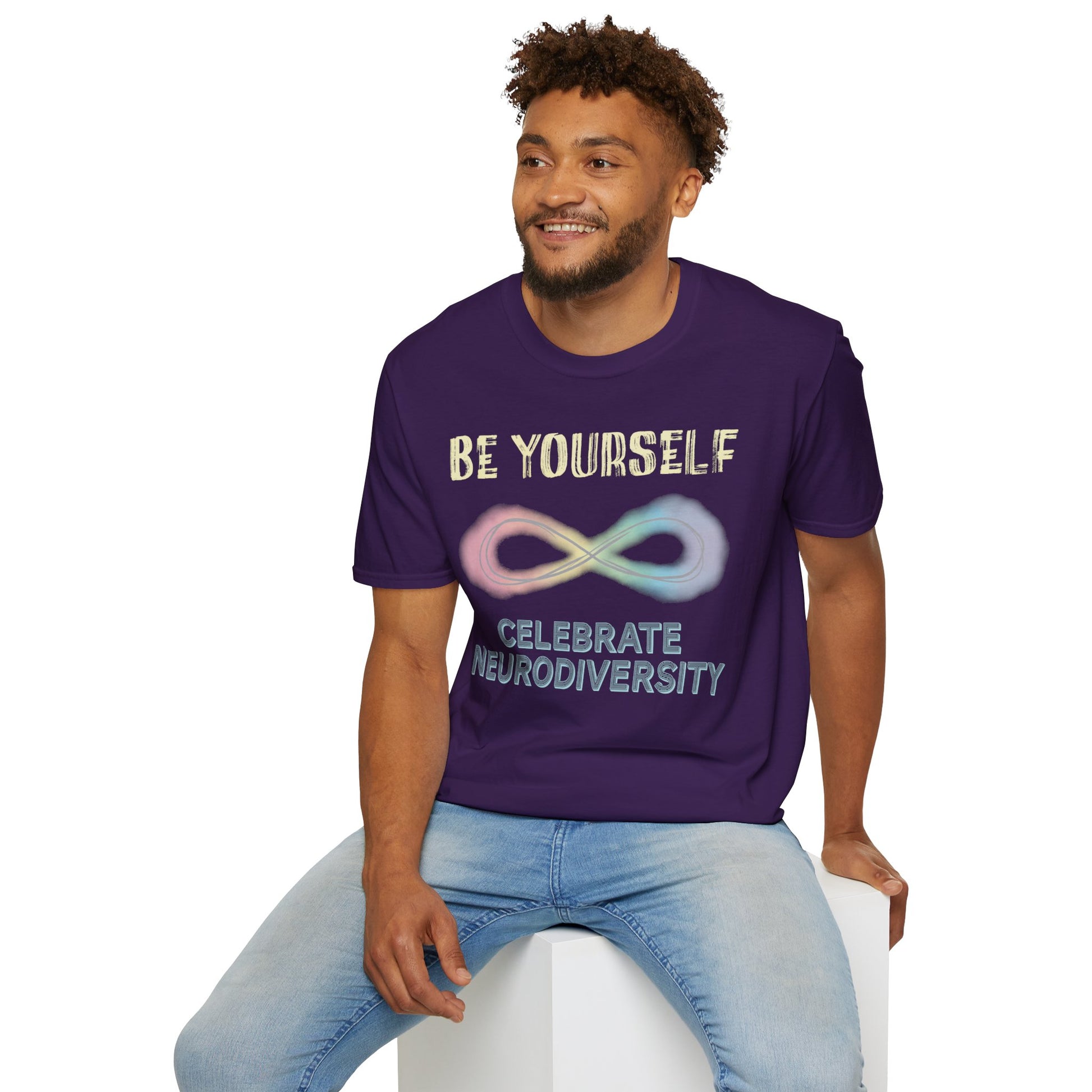 Man wearing a dark purple t-shirt featuring a pastel-colored rainbow infinity symbol, with the text 'Be yourself, celebrate neurodiversity'.