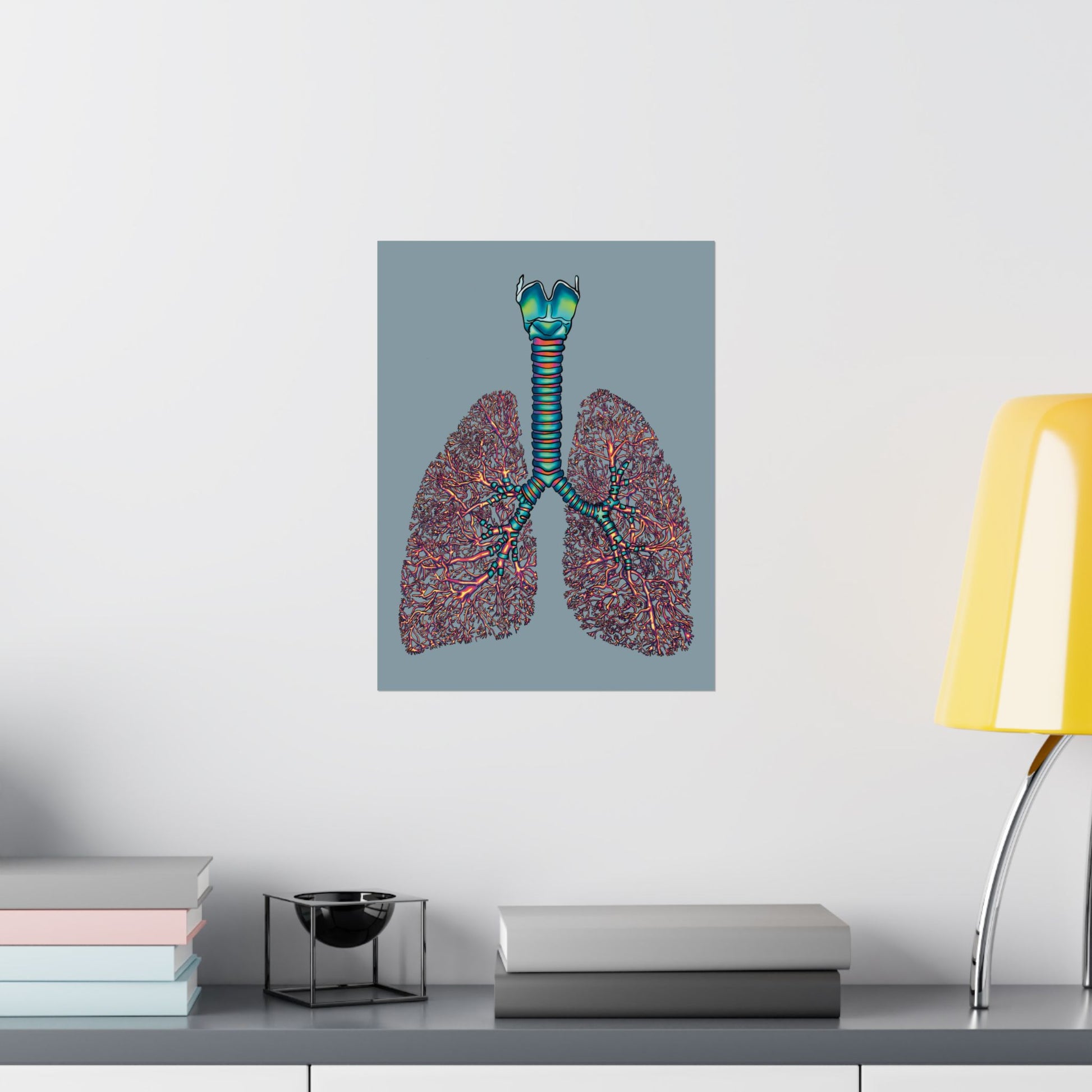 Small poster displayed on a wall in an office setting, featuring an illustration of anatomical lungs with detailed bronchial tree, trachea, and larynx, set against a blue-grey background.