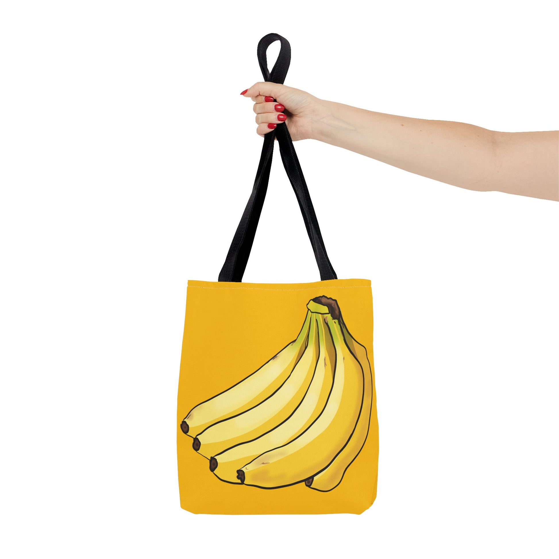 Woman holding a small yellow tote bag out to the side featuring a playful illustration of a bunch of bananas on the front, set against a solid yellow background.