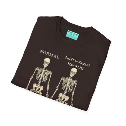 Folded brown unisex short sleeve t-shirt featuring two skeletons side by side—one labeled "normal," the other "Ehlers-Danlos Syndrome"—because connective tissue disorders deserve more visibility (and maybe a sense of humor, too).