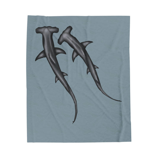 A cozy blue-grey velveteen plush blanket featuring two hammerhead sharks gliding through the fabric like it's their personal ocean—perfect for wrapping yourself in comfort with a side of bite.