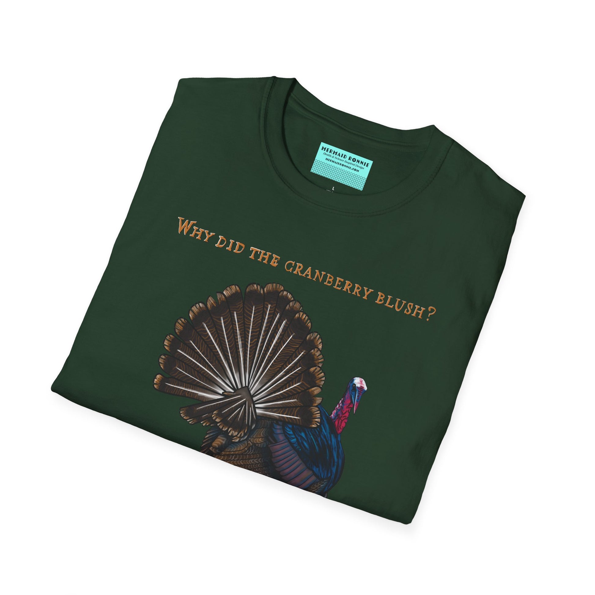 Folded green Thanksgiving t-shirt featuring a picture of a turkey and the text 'Why did the cranberry blush? Because it saw the turkey dressing!