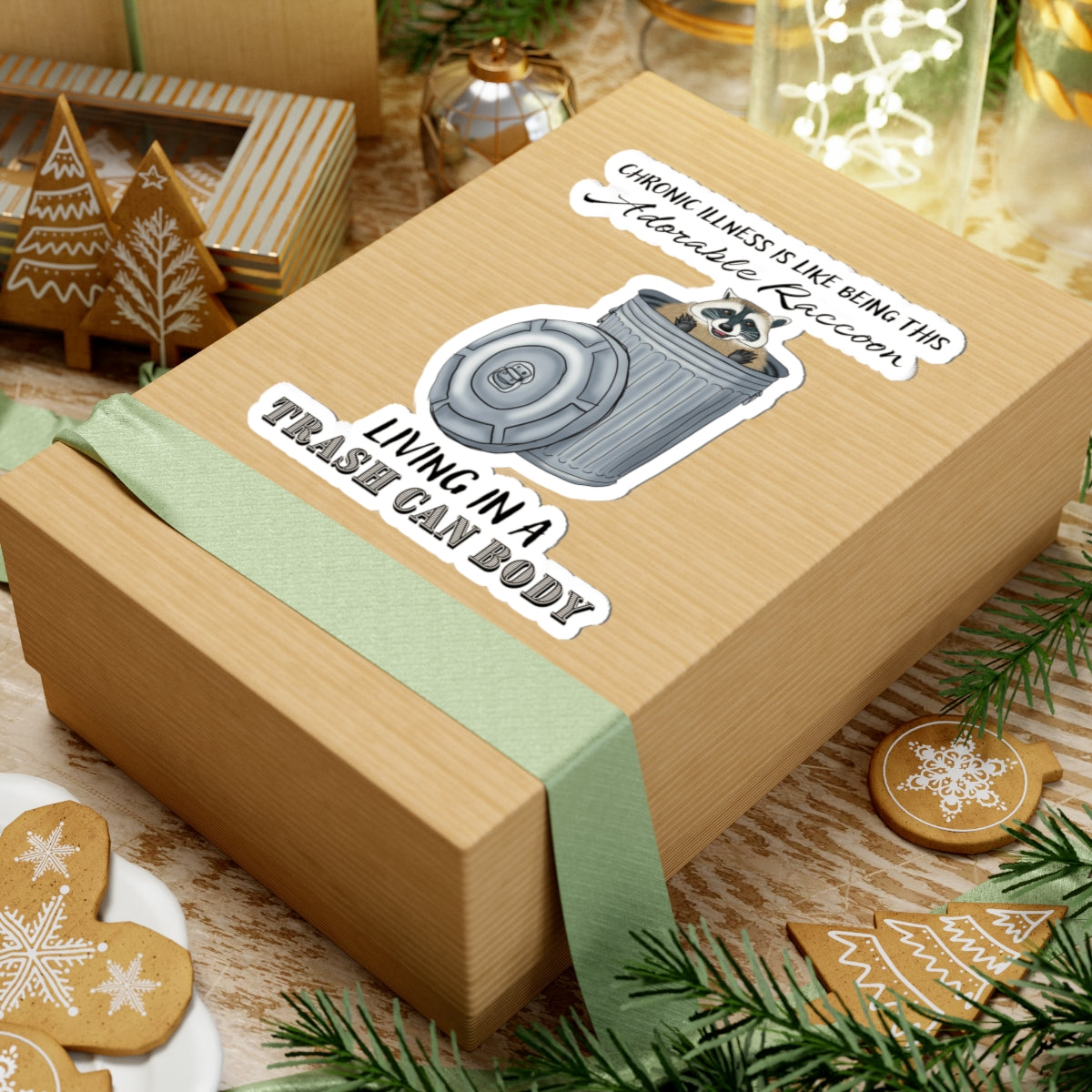 Large sticker on a gift with a drawing of a raccoon sitting in a metal trash can, accompanied by the text: 'chronic illness is like being this adorable raccoon living in a trash can body.'