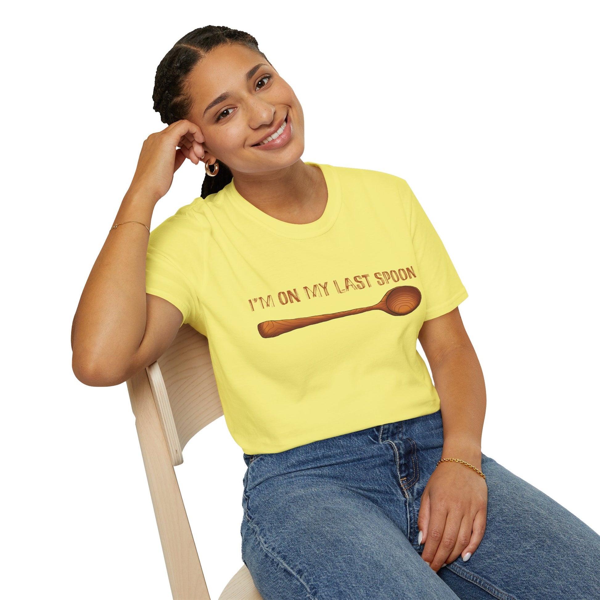 Woman wearing a yellow t-shirt with an illustration of a single wooden spoon and the phrase 'I'm on my last spoon' printed on the front.