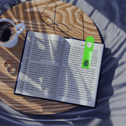 Lime green aluminum bookmark in use featuring a detailed illustration of a June bug (green chafer beetle), its iridescent body gleaming against the vibrant background.