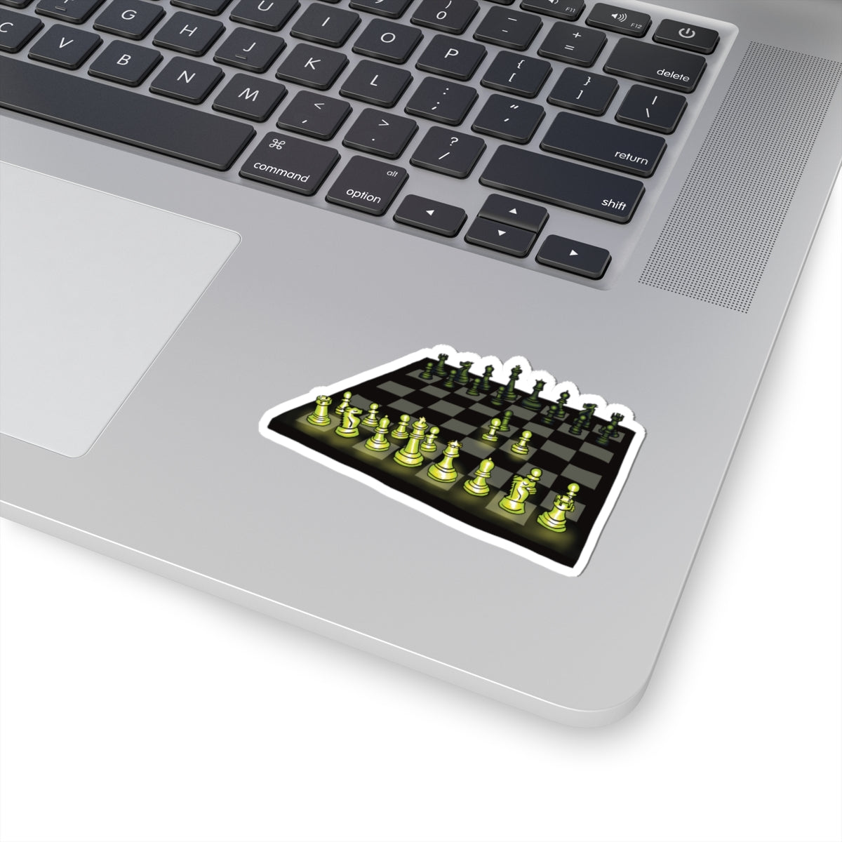 Small sticker on a computer featuring a drawing of a chessboard with pieces illuminated by green light, showing the opening move known as the Queen’s Gambit.